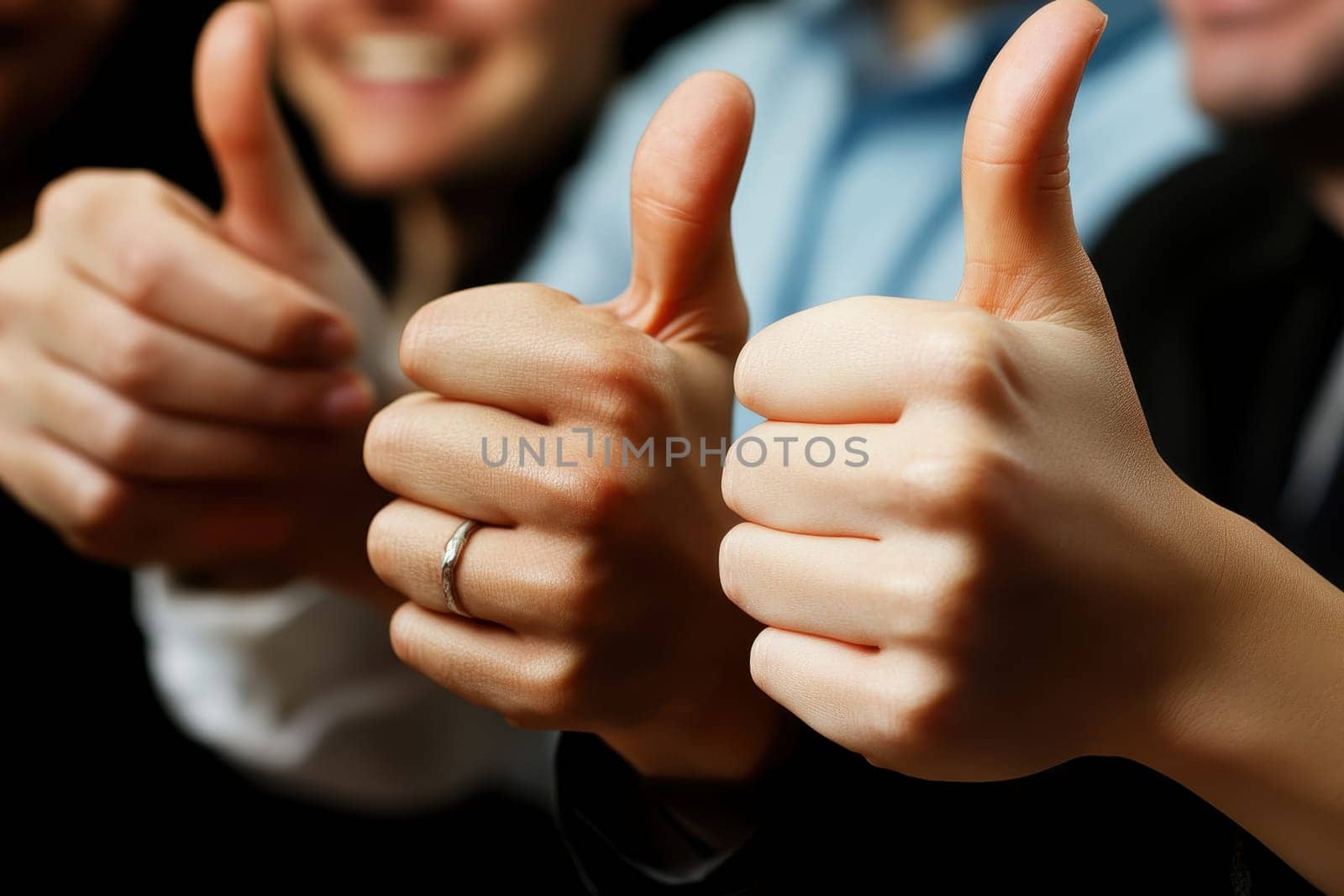 A close-up view of hands showing thumbs up, symbolizing positivity and approval in a group setting. This gesture reflects teamwork, success, and celebration.