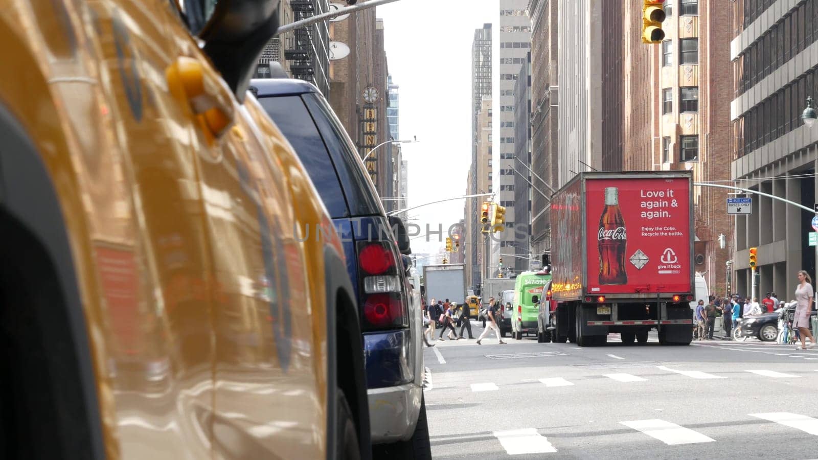 New York City, United States - 11 Sept 2023: Yellow taxi car on Manhattan street. Taxi cab on Midtown Lexington Lex avenue. Medallion taxicab. Urban road scene. Coca-Cola red truck, Cola or Coke, USA.