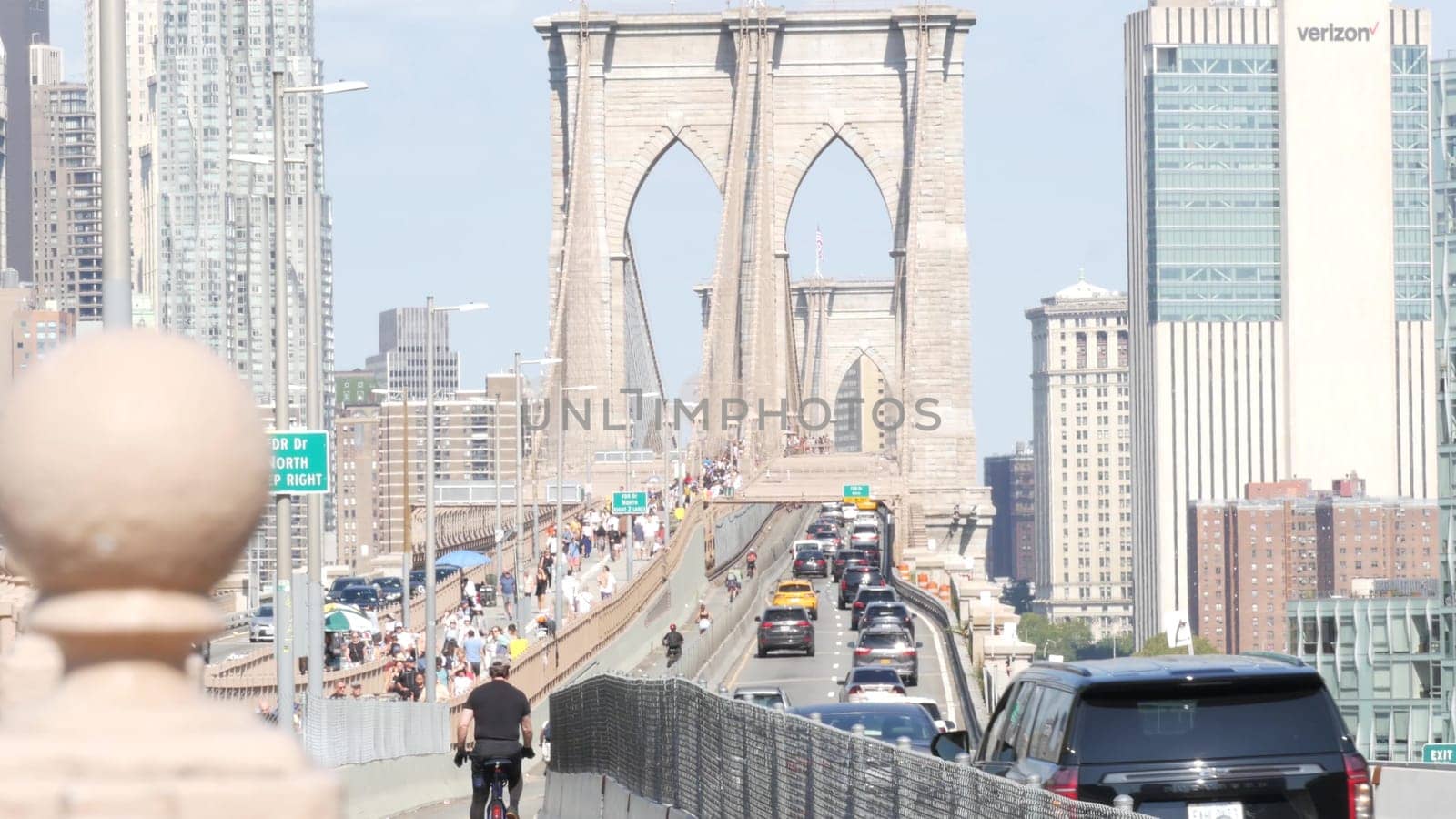 New York City, United States - 3 Sept 2023: Cars on Brooklyn Bridge from Manhattan downtown to Dumbo. Financial district skyline cityscape. Road traffic, people walking and USA architecture.