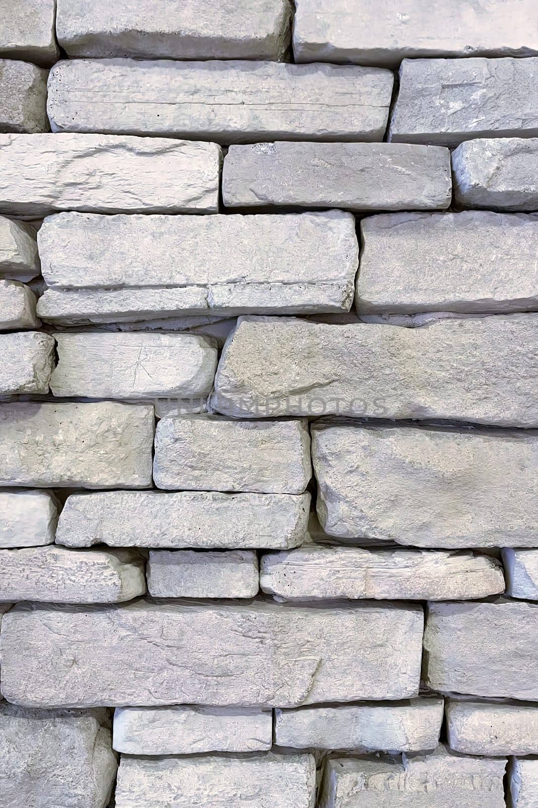 Textured Stone Wall Background.A close-up view of a textured stone wall. The wall is constructed from irregularly shaped, light-colored stones that are stacked in a horizontal pattern.