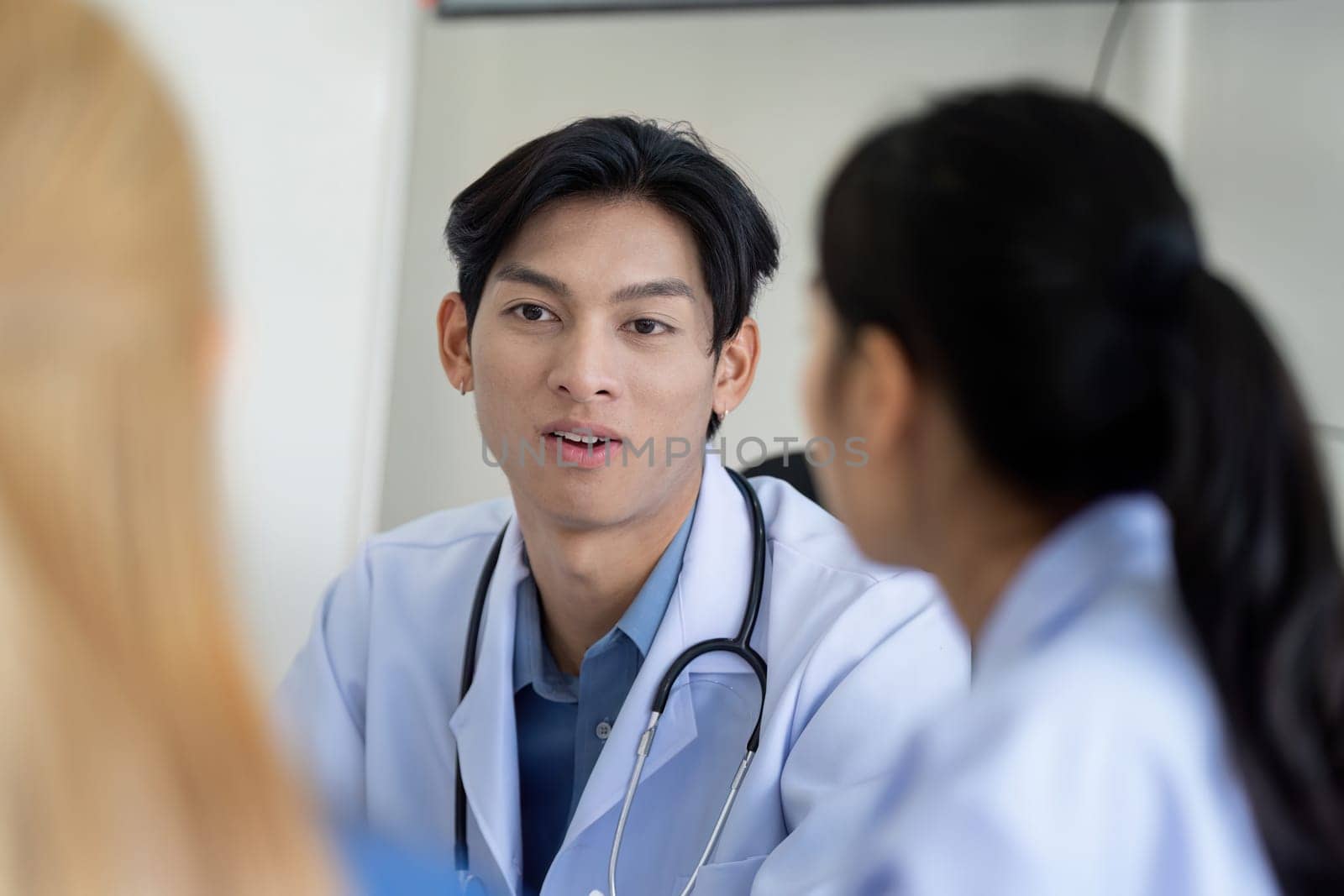 A doctor is engaged in a collaborative discussion with colleagues during a healthcare planning meeting, focusing on patient care and strategies in a clinical environment.