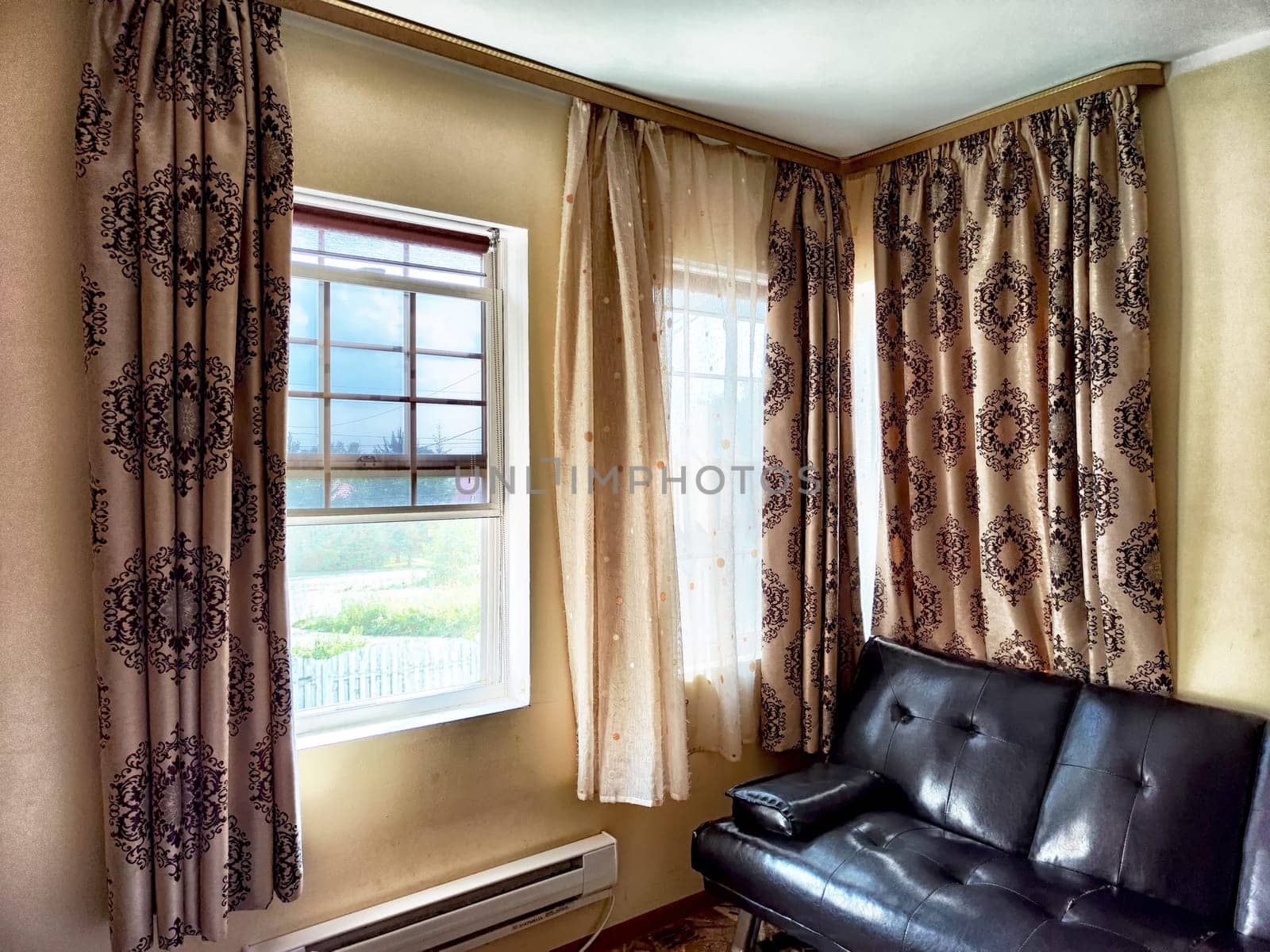 A warm living space featuring elegant curtains and a comfortable black leather sofa enhancing the inviting atmosphere.
