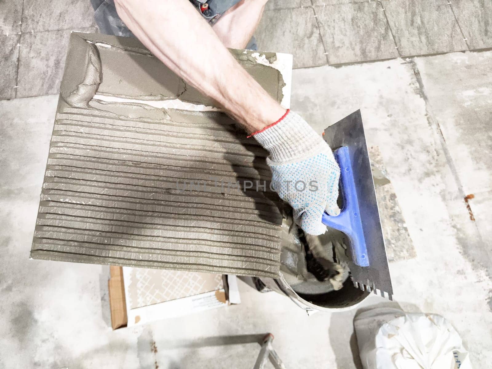 A worker applies mortar with a trowel to prepare for tile installation in a residential space showing the repair process at close range.