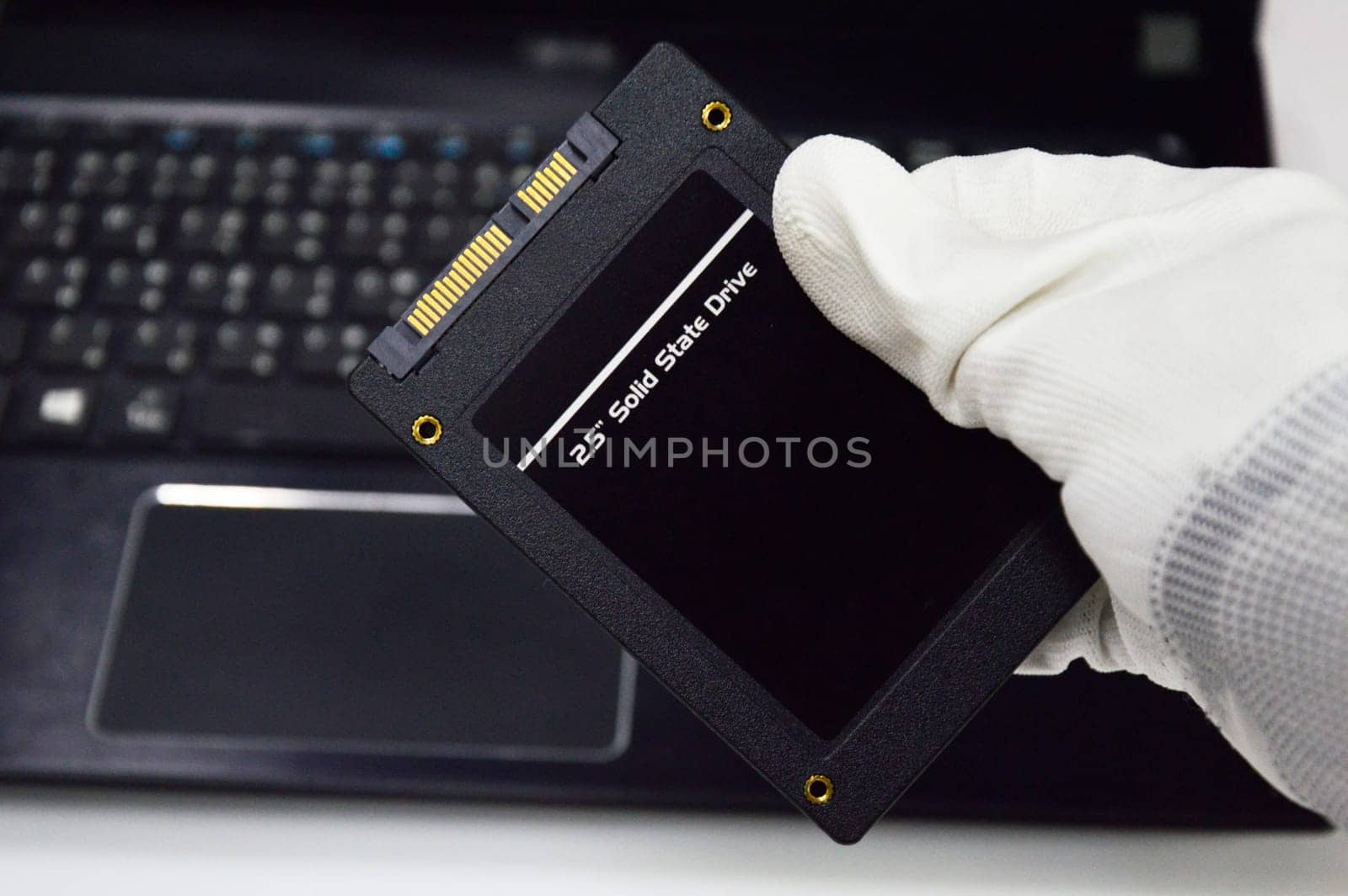 Harddisk SSD 2.5 inch black that is holding in hand.