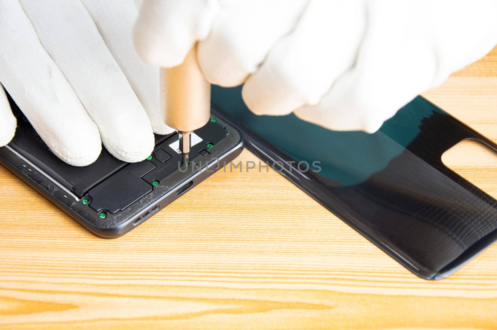 Image of a technician screwing the back of a mobile phone