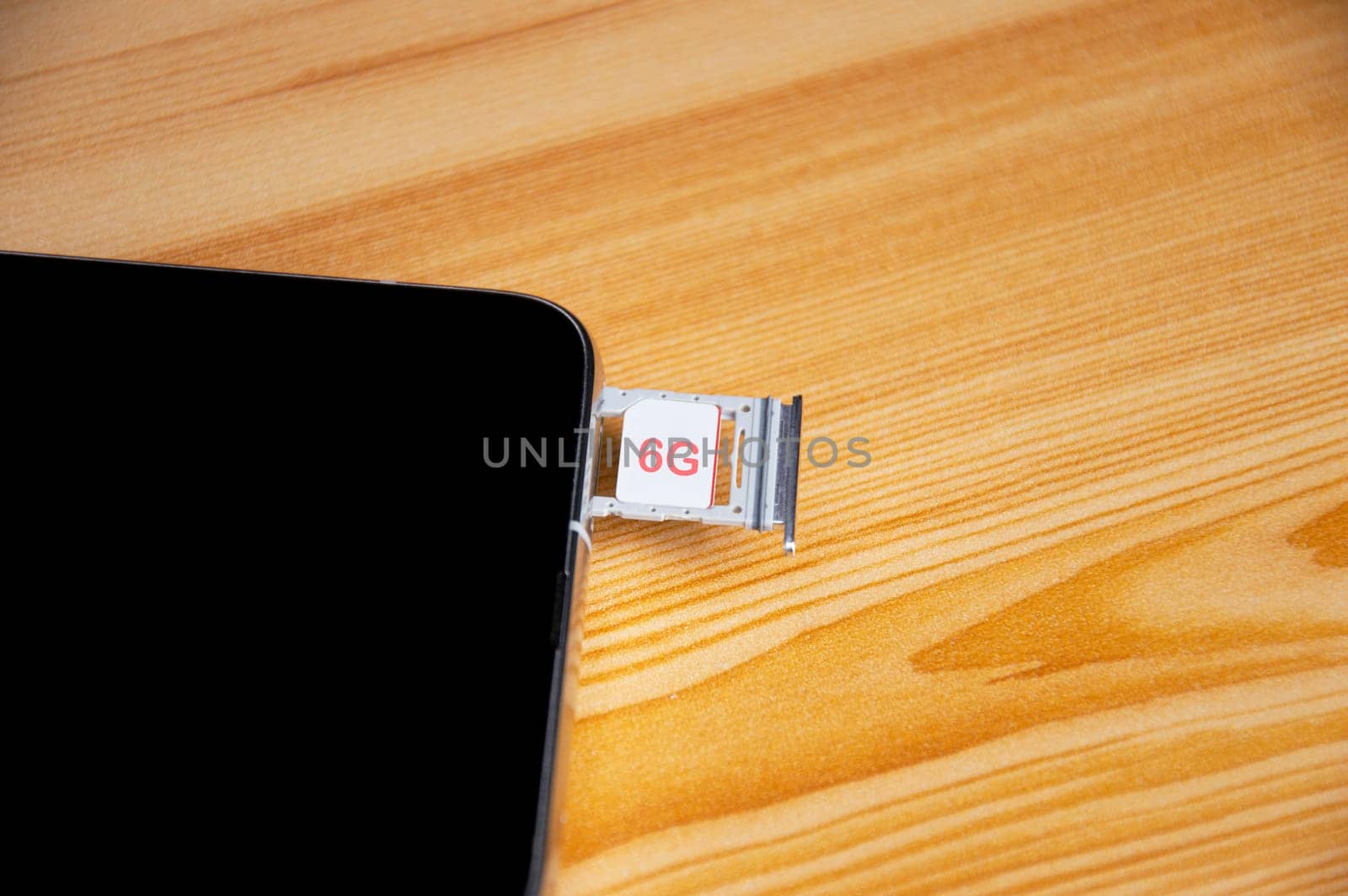 6G technology, Internet concept. SIM card in smartphone tray on wooden table, closeup 6G network concept, high speed mobile internet New age network, business concept, modern technology internet and network