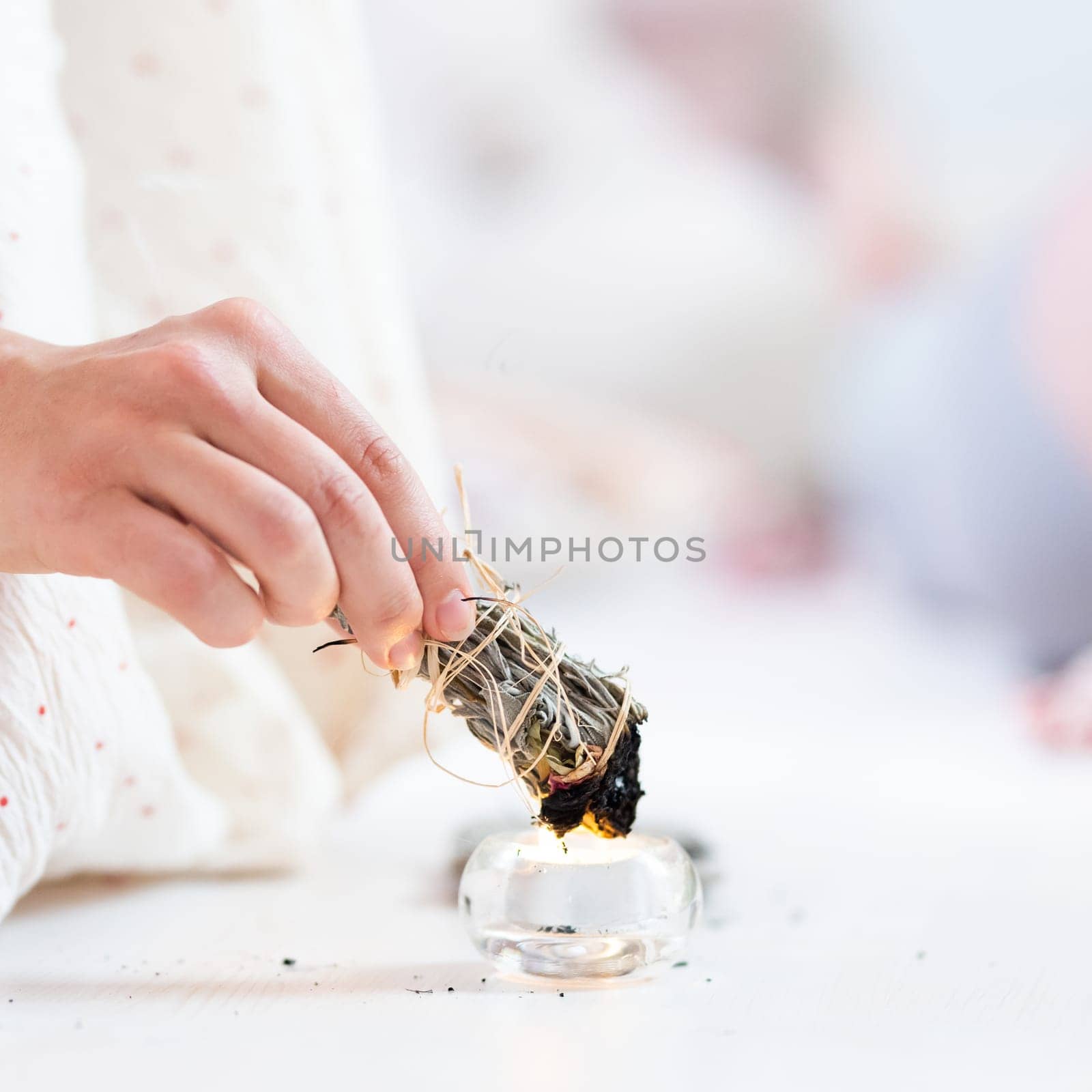 Woman lighting a smudge kit with herbal stick. Natural elements for cleansing environment from negative energy, adding positive vibes. Spriritual wellness practices