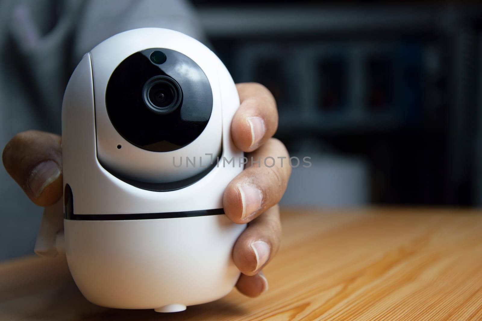 White ip camera lies on wooden floor, man using ip camera