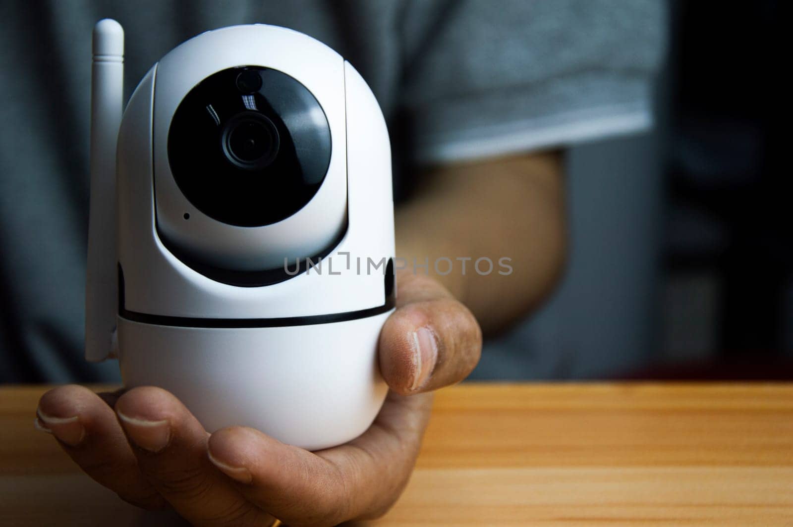 White ip camera lies on wooden floor, man using ip camera