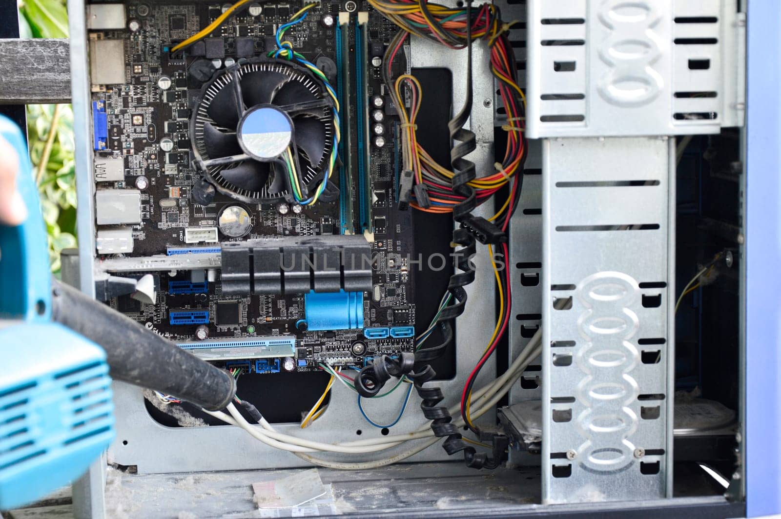 Photograph of a technician blowing dust from a computer