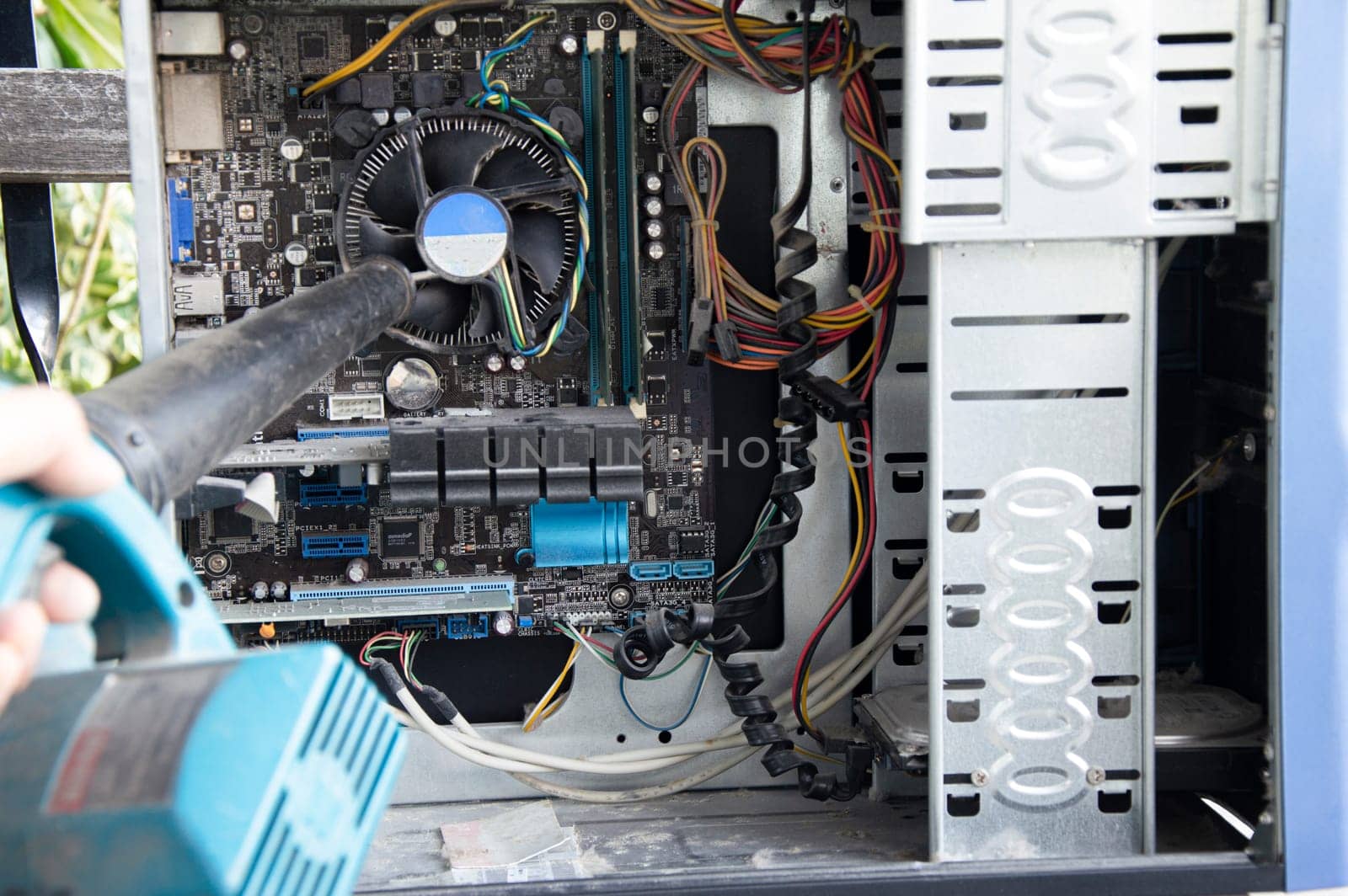 Photograph of a technician blowing dust from a computer