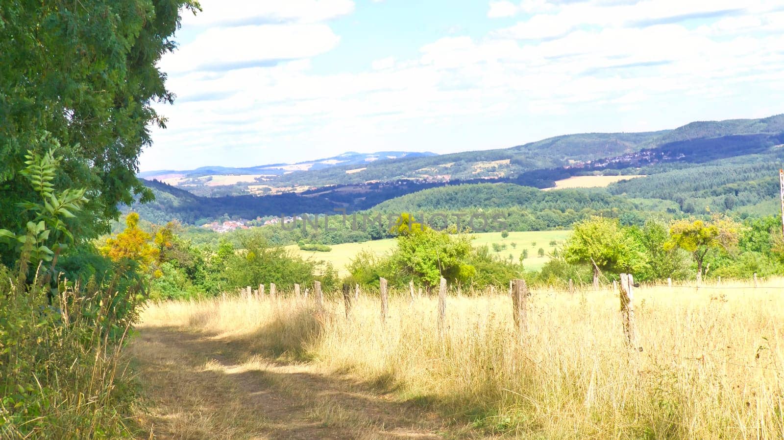 Vast landscape with green forests, rolling hills and a blue sky with white clouds. Idyllic nature, peace and freedom in a summery setting.