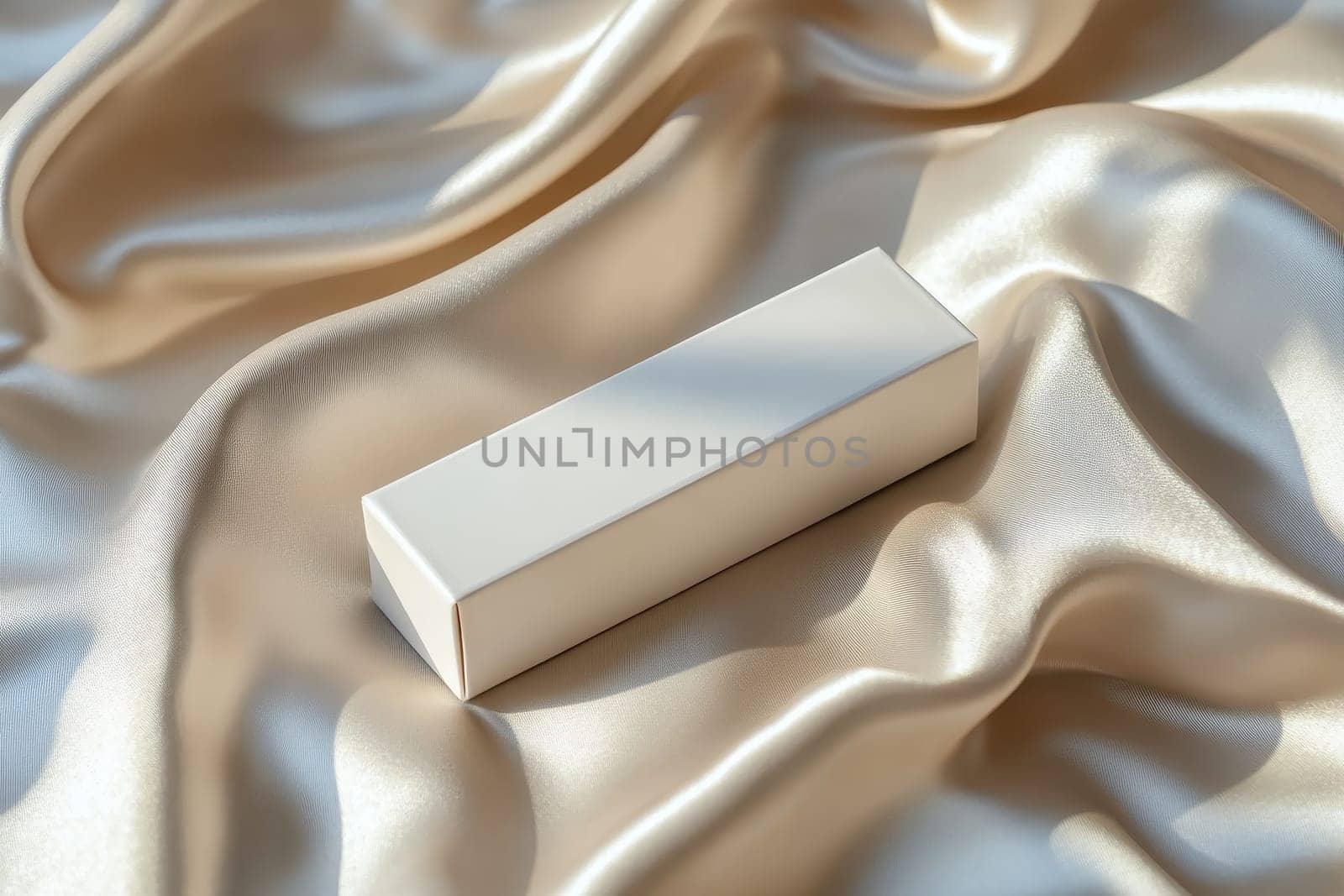 A white box is on a piece of silk fabric. The box is empty and the fabric is smooth and shiny