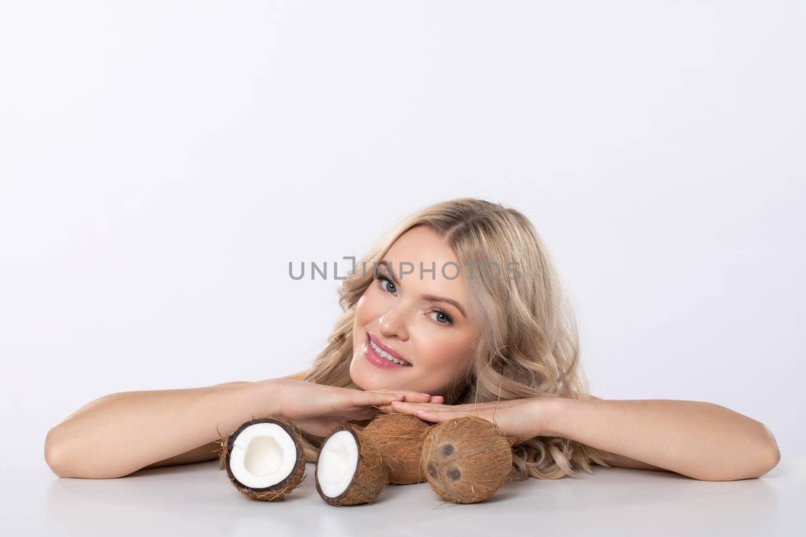 A woman with a bright, cheerful smile holds fresh coconuts, celebrating the essence of natural beauty and health