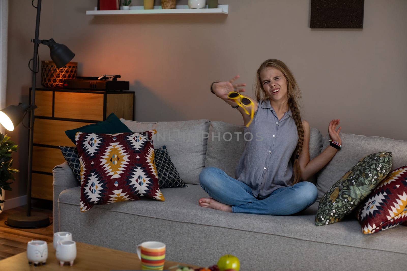A woman is sitting back comfortably on a cozy couch, happily enjoying the warm ambiance of her lovely living room