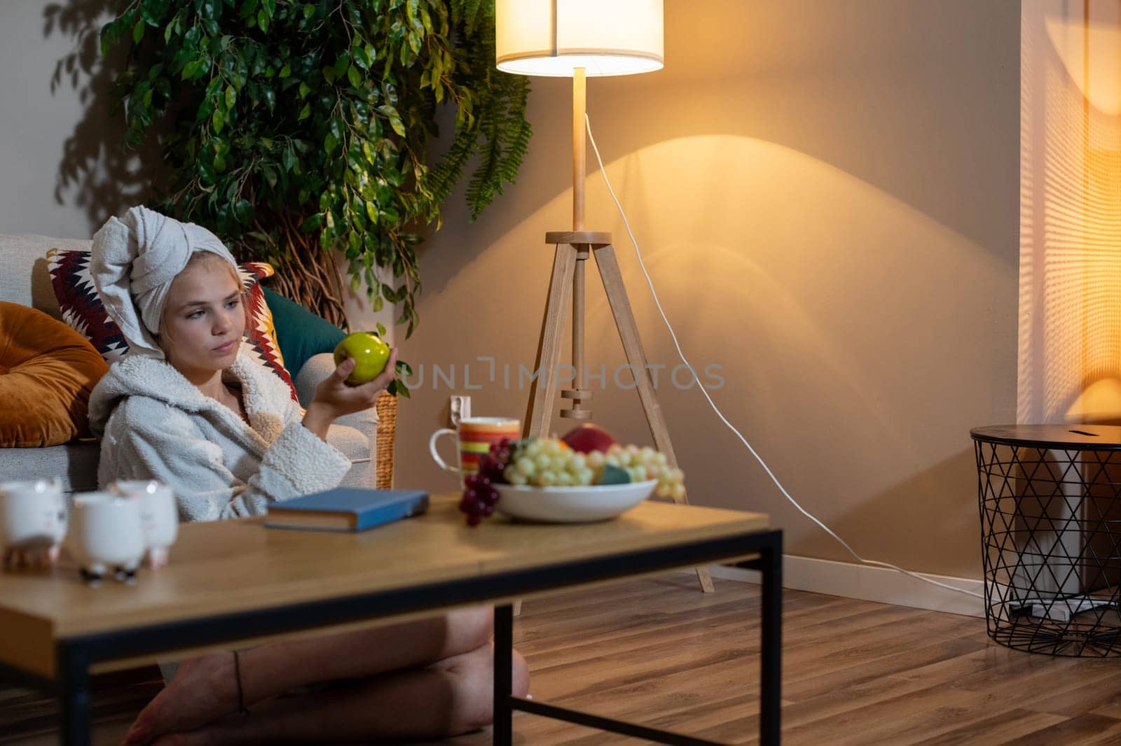 A woman is savoring a cozy, relaxing evening at home surrounded by fresh fruits and a tranquil ambiance