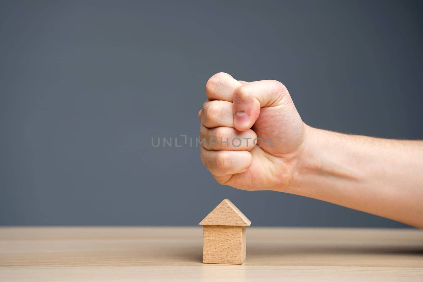 The fist aims at the house. Сollectors. Concept of threat to house and real estate and business. The threat of a strike at prices. Aggression on the market.