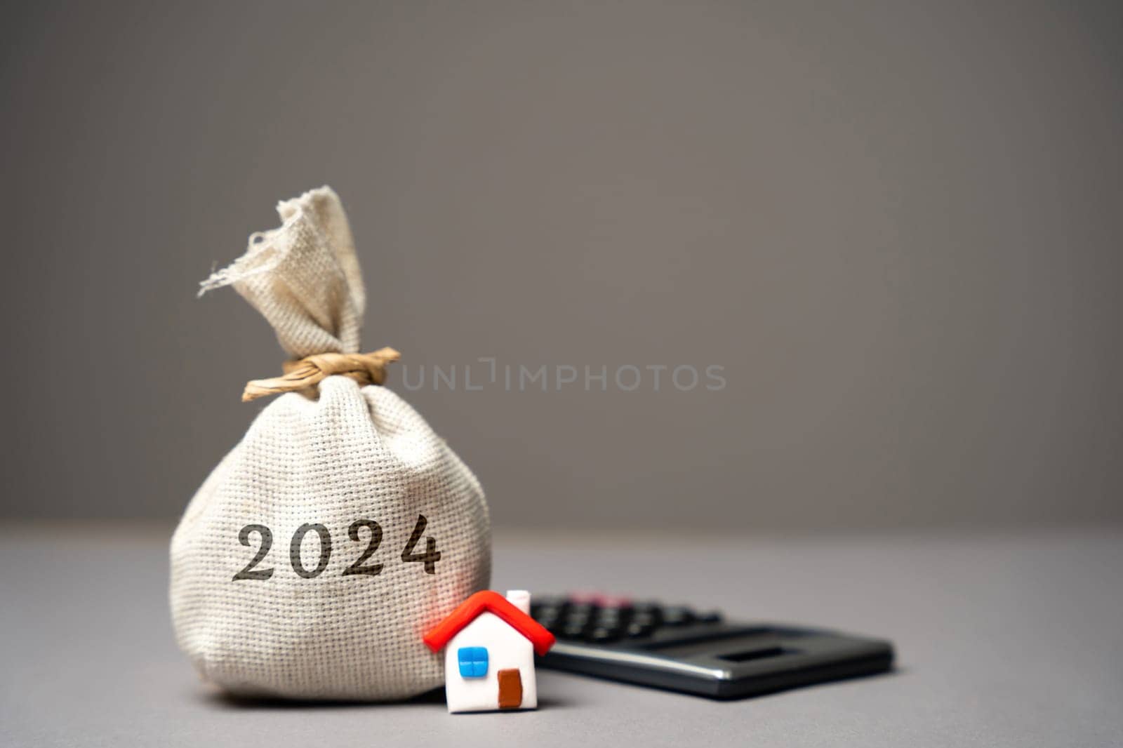 2024 budget real estate concept. Family budget planning. Investments, plans, savings. Mortgage and mortgage rates. Forecasts. Loan. Refinance home. Money bag and miniature house.