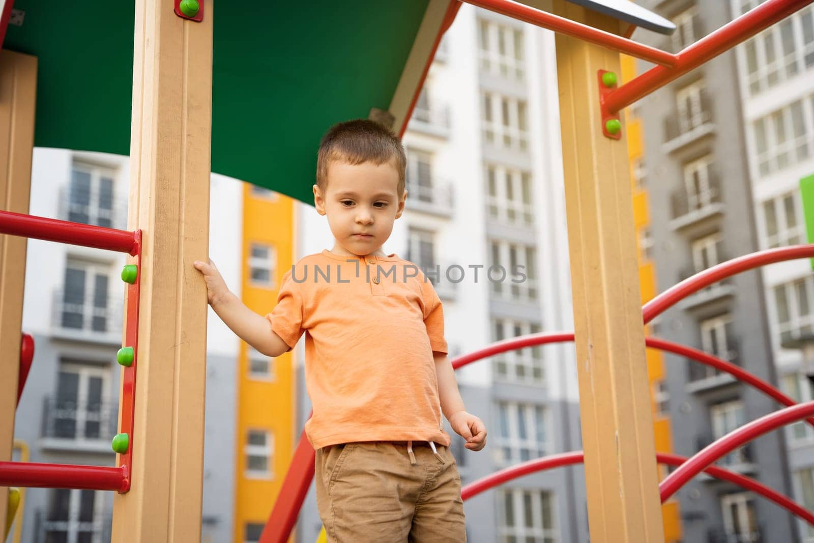 Cute toddler boy two or three years old is playing on the playground in a residential complex. Healthy summer activity for children. Children's games. Selective focus
