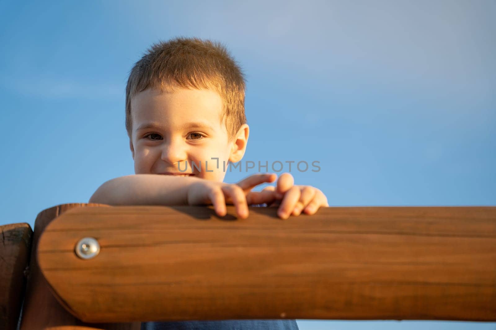 Portrait of a happy smiling toddler boy of two or three years old against the blue sky on a sunny day. Lifestyle and happy childhood concept. Copy space