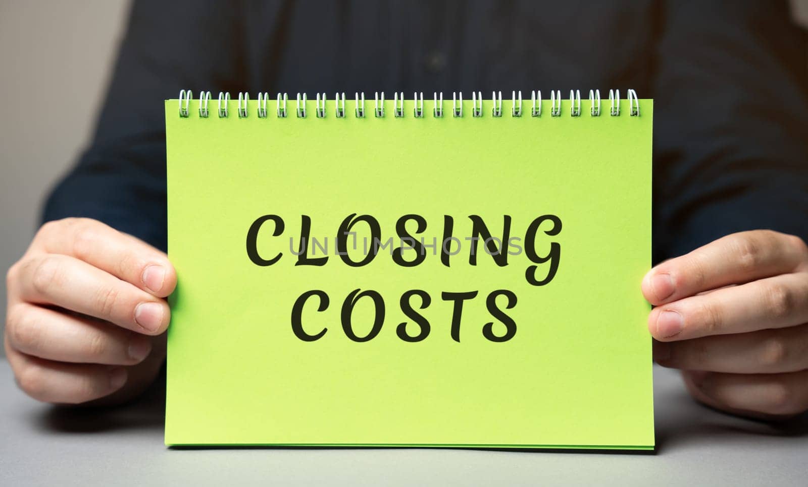 Closing costs concept. Extra amount of money that you pay when buying a house. Real estate and finance concept. Note in the hands of a businessman