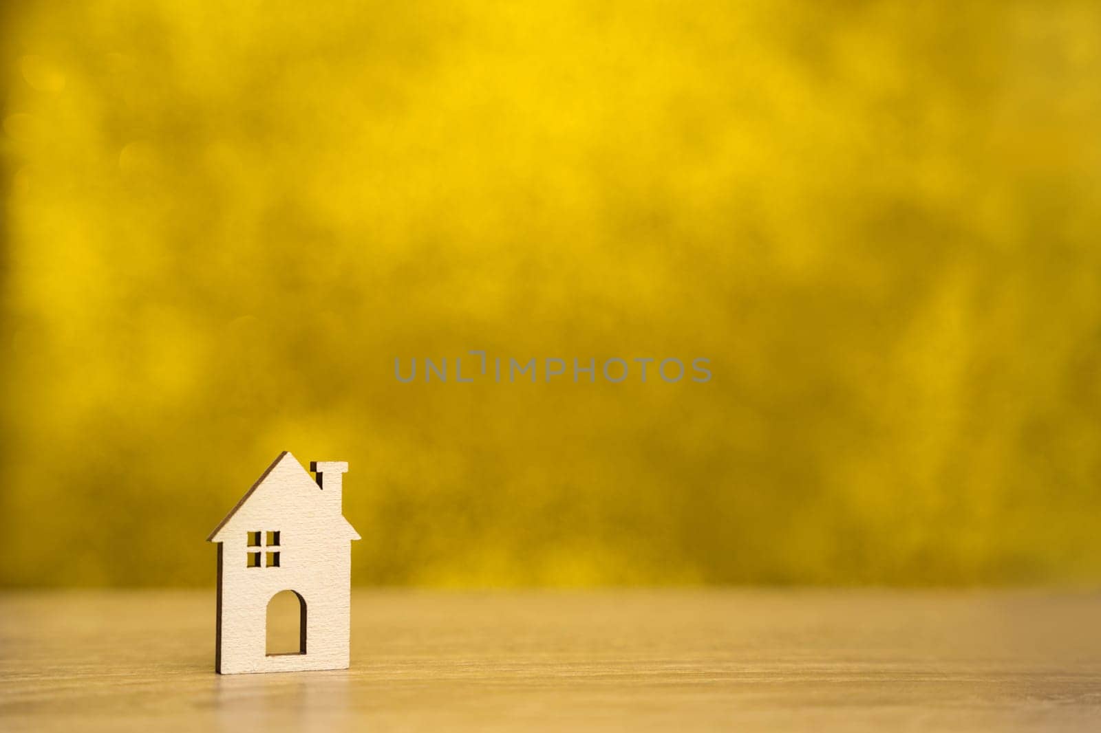 Miniature wooden house on a yellow background. Real estate and affordable housing concept. Mortgage, loan and insurance of apartments. Selling and buying home. Copy space