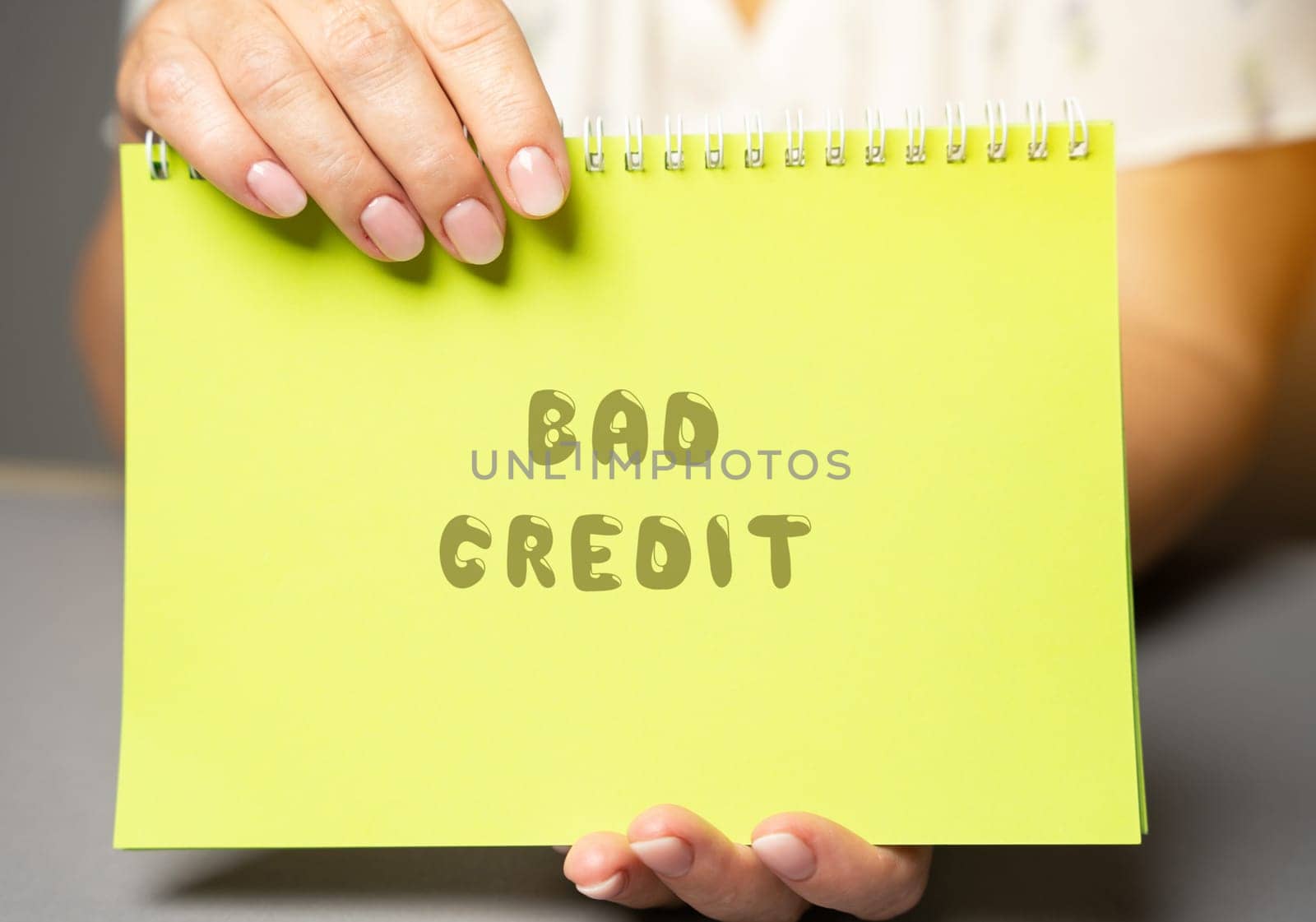 The inscription Bad credit in a notepad. Credit and loan concept. Business and finance. Woman's hand holding a notepad