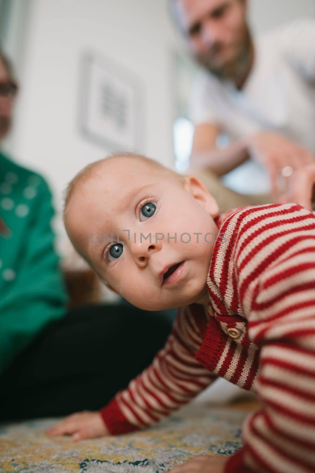 A curious little baby crawls eagerly across the soft floor, engaging joyfully with family in a warm, inviting space