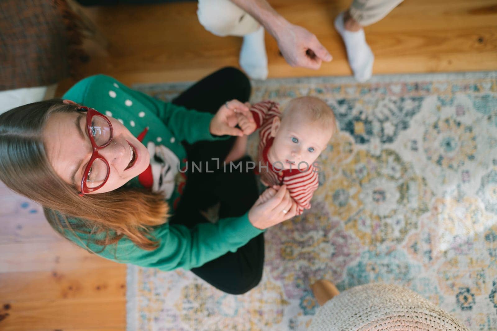 A joyful and heartwarming moment capturing a woman wearing glasses, as she plays with a baby indoors