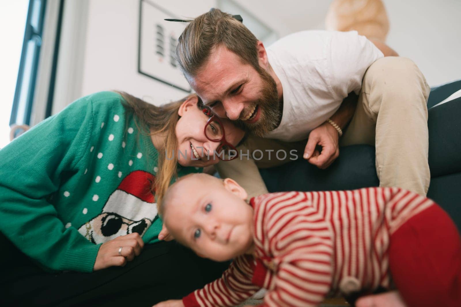 A happy family captures a fun moment with their adorable baby at home, showcasing their love and bond