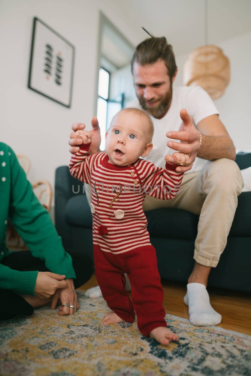 A joyful moment of a baby learning to walk for the first time, supported by family in a warm, cozy home