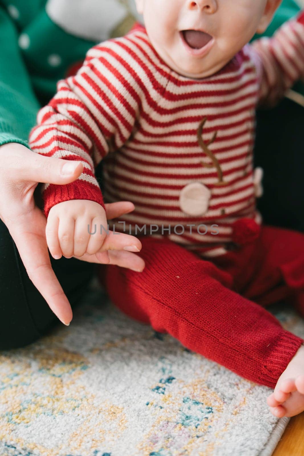 A happy child in festive attire joyfully interacts with an adult's hand, capturing warmth and connection.