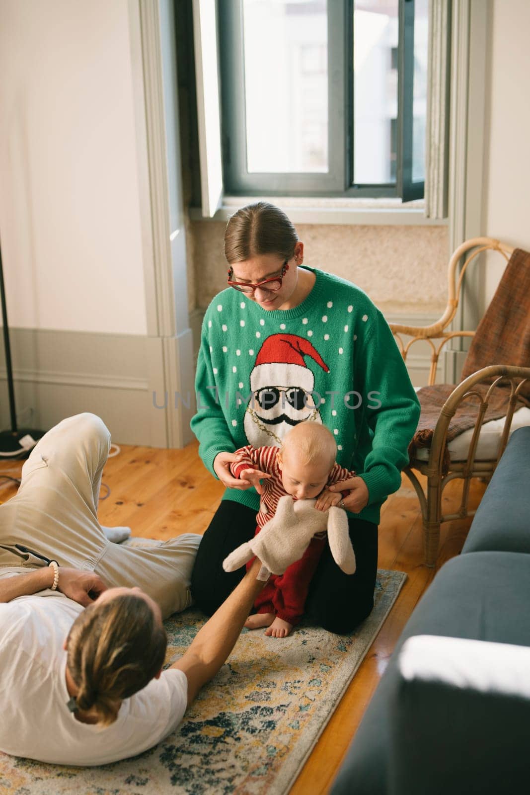 A joyful scene of a family bonding in festive attire alongside a cute, playful doll for the holiday season