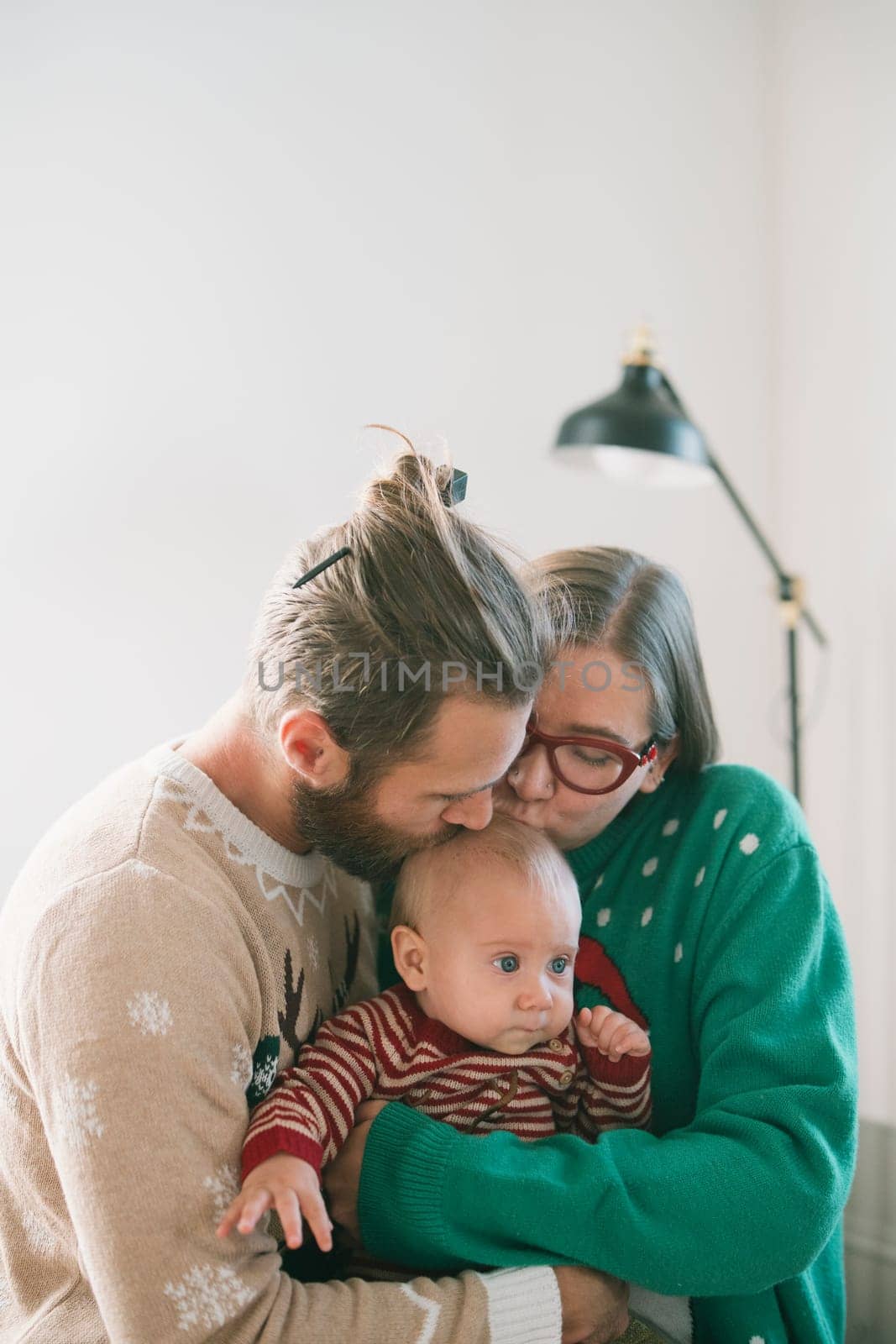 A beautiful moment of a loving family joyfully hugging their adorable baby, celebrating togetherness in festive outfits