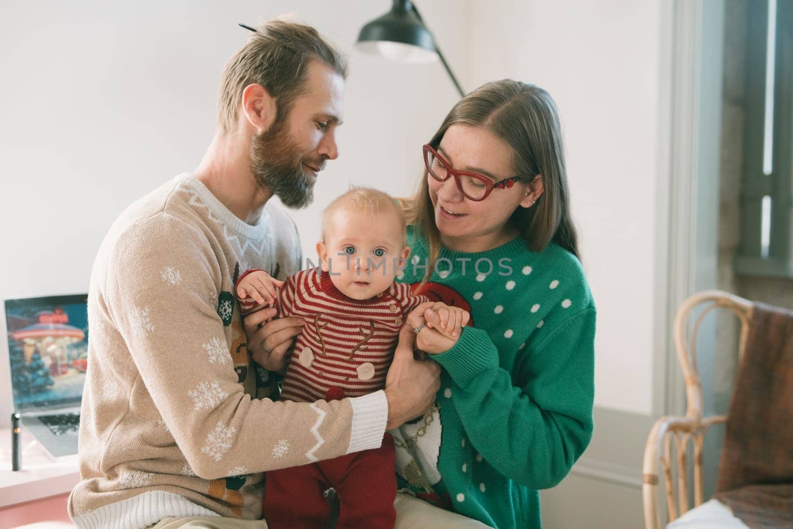 A loving family of four enjoys quality time in colorful holiday sweaters, creating lasting memories with their baby