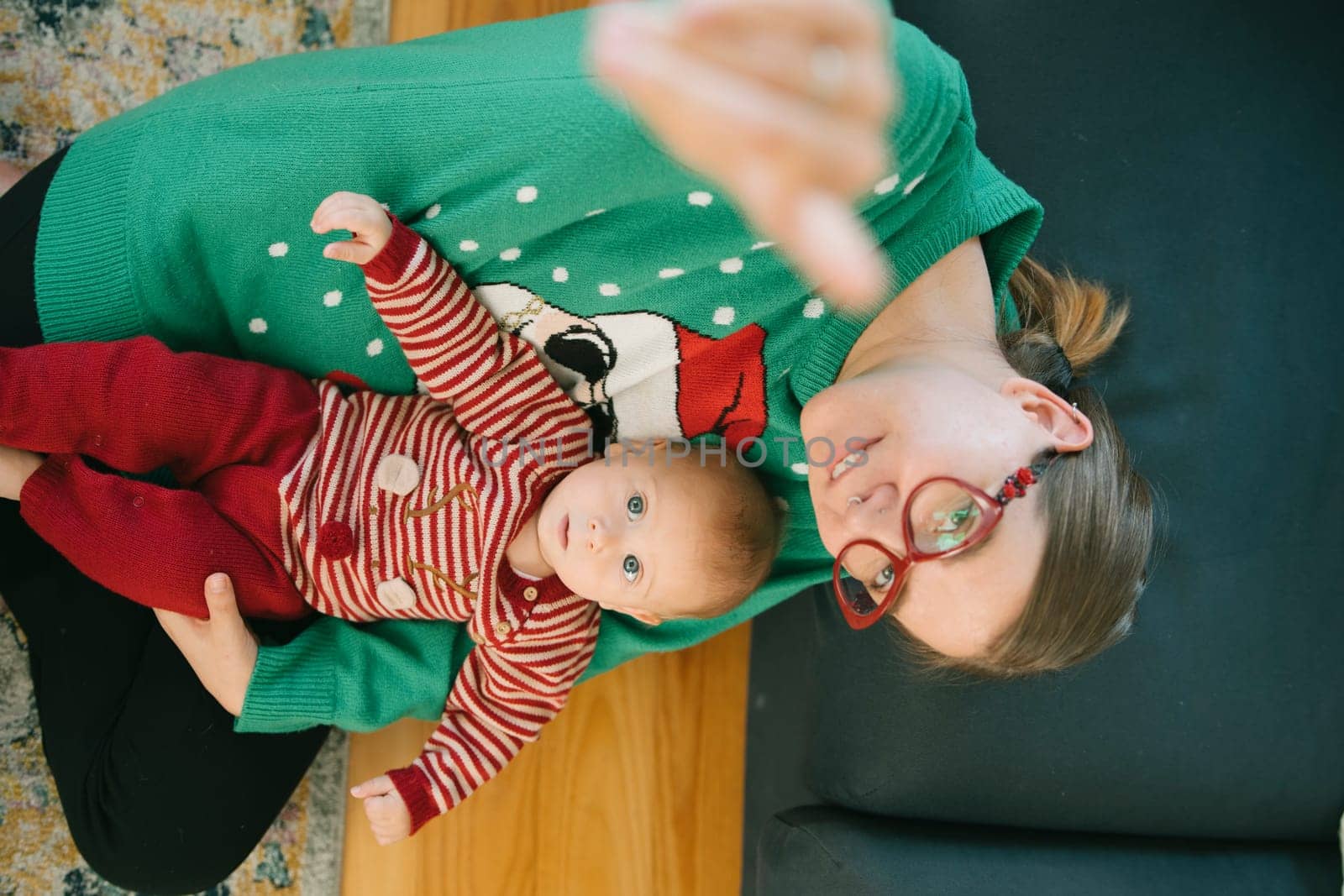 A joyful mother and her adorable baby enjoy a cozy cuddle in festive outfits within a warm, inviting setting