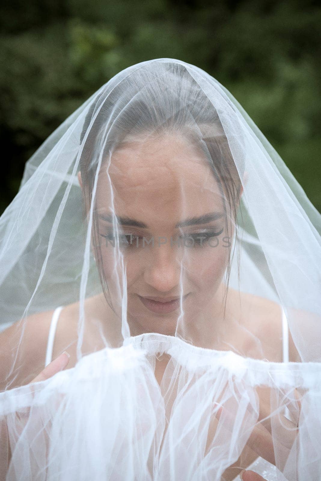 A person with pink hair looking at the camera. High quality photo, close-up of bride covered with white veil. beautiful brunette girl with smooth hair and stylish make-up.