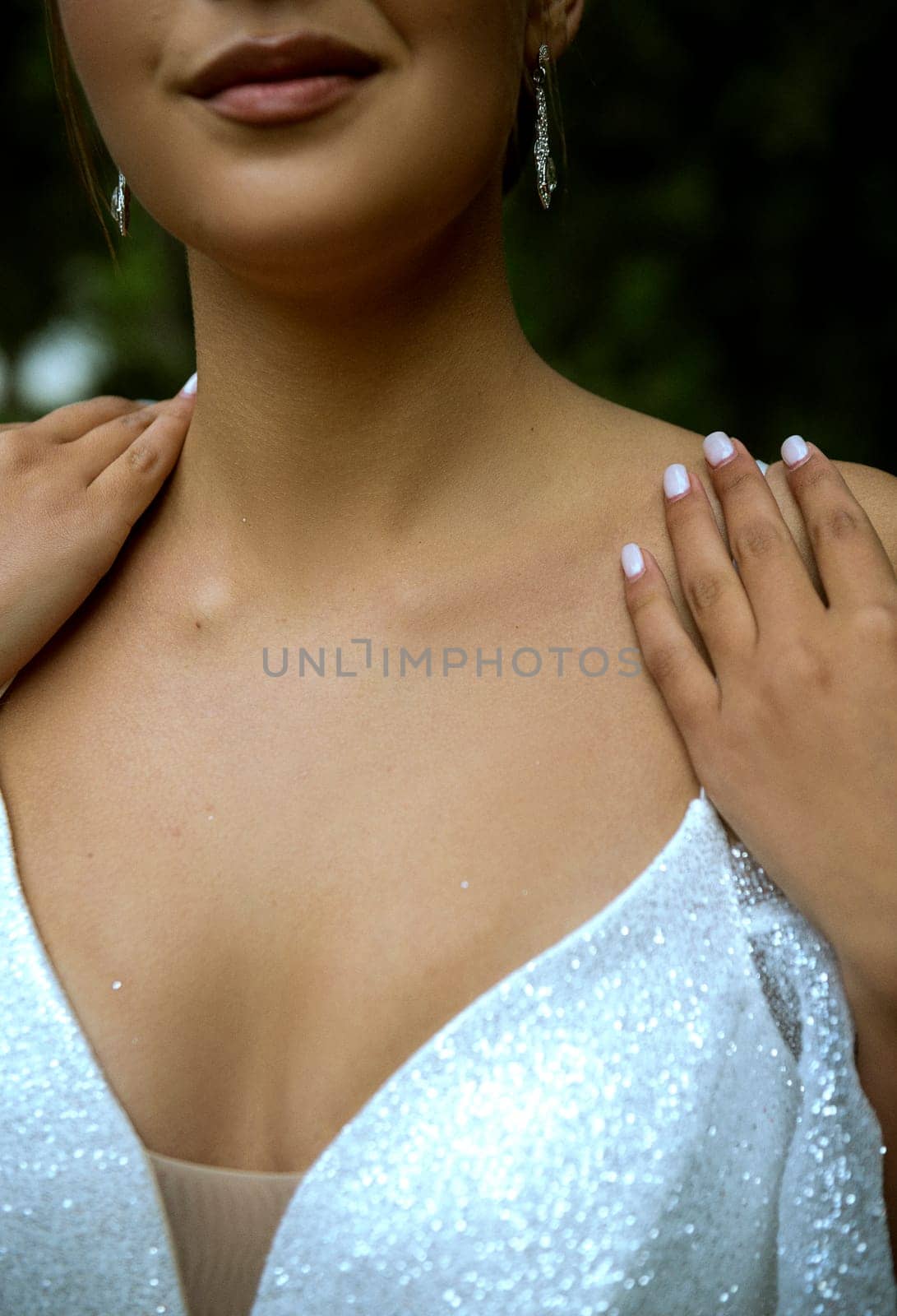 close-up of bride's body detail, lips and shoulders. beautiful young tanned skin. white elegant dress with straps. perfect light manicure on her hands