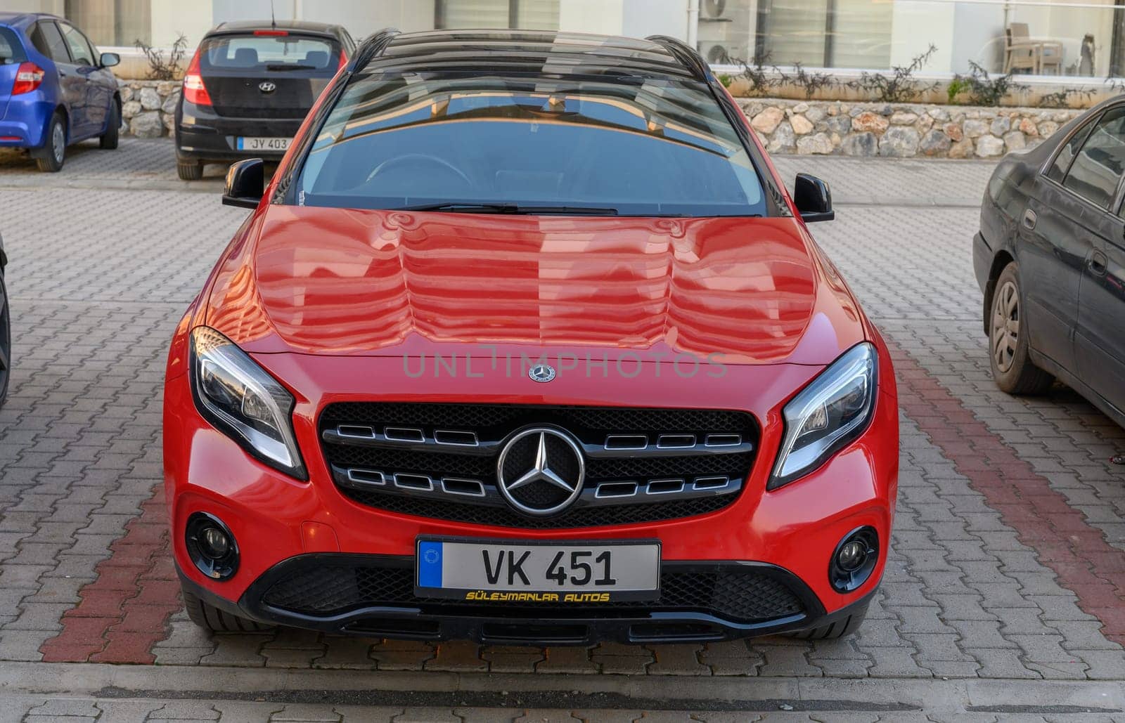Gaziveren Cyprus -30.01.2025 A sleek red luxury car stands out against a backdrop of contemporary buildings amidst the evening glow.