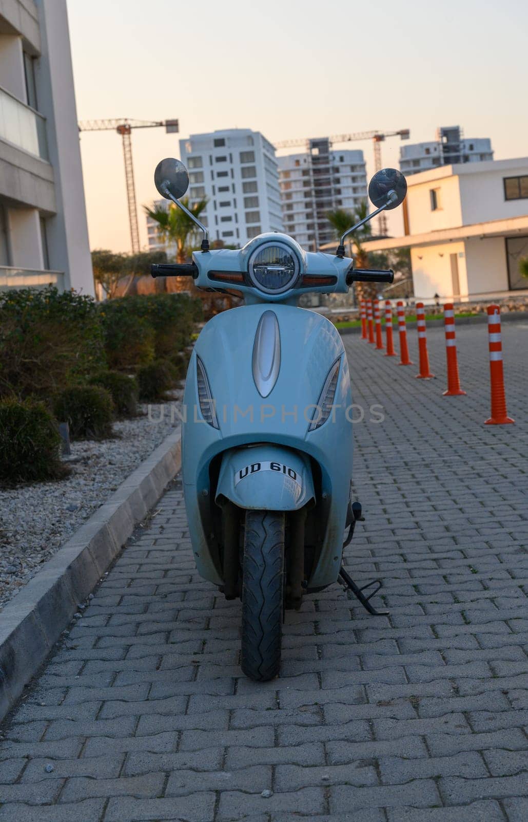 Gaziveren Cyprus -30.01.2025 A sleek, pastel-colored electric scooter stands proudly on a contemporary brick pathway at sunset.