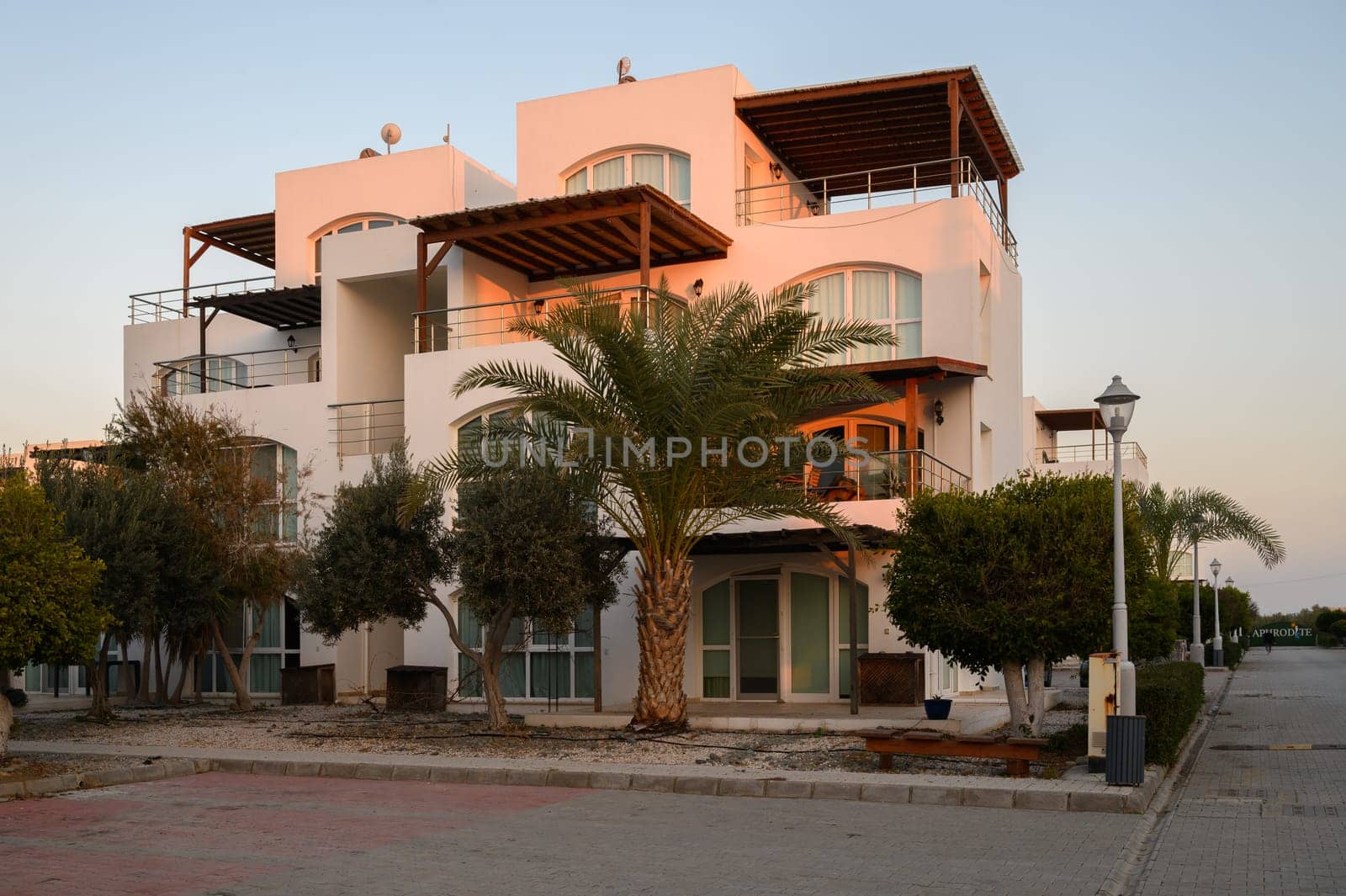 Modern architecture stands amidst palm trees at dusk in a serene coastal setting.