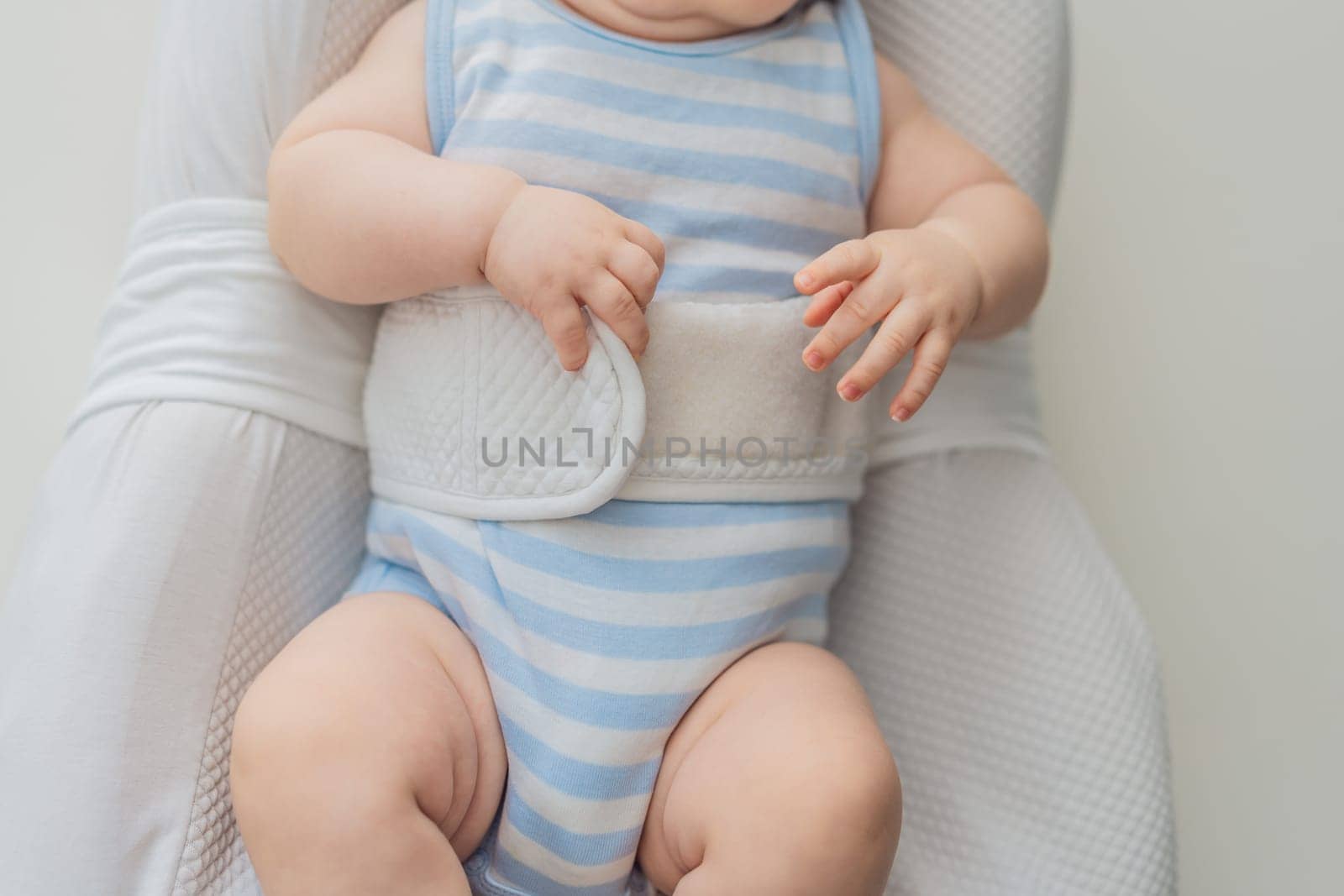 Adorable 3-month-old baby lying safely in a cozy infant cocoon secured with a special safety belt. Comfortable and protective design for newborn care. Parenting, safety, and baby comfort concept.