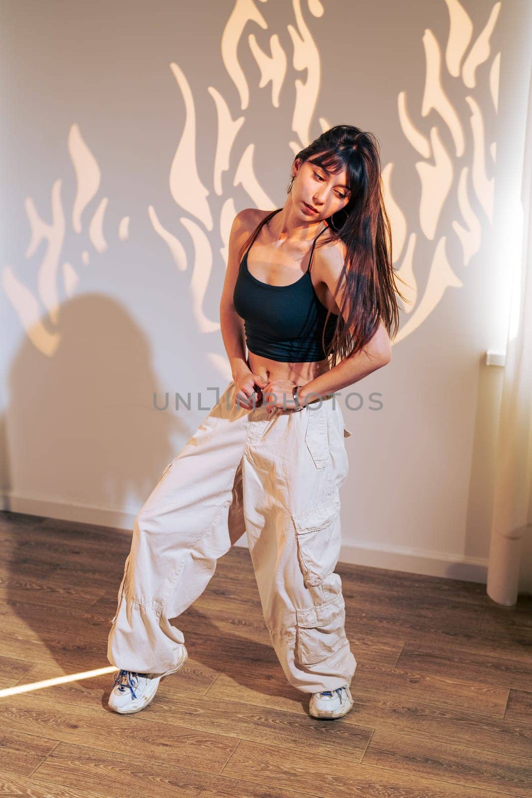 A dancer showcases her skills in a chic room, wearing casual attire. The warm light creates intriguing flame-like shadows, enhancing the artistic atmosphere as she moves gracefully.