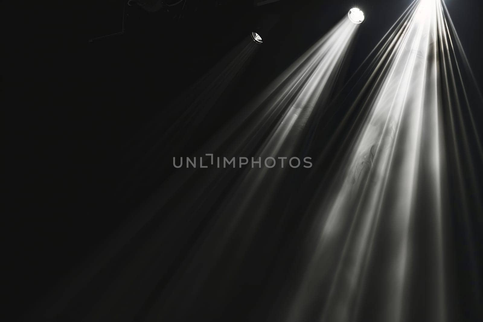 Light beams shining on stage in dark environment.