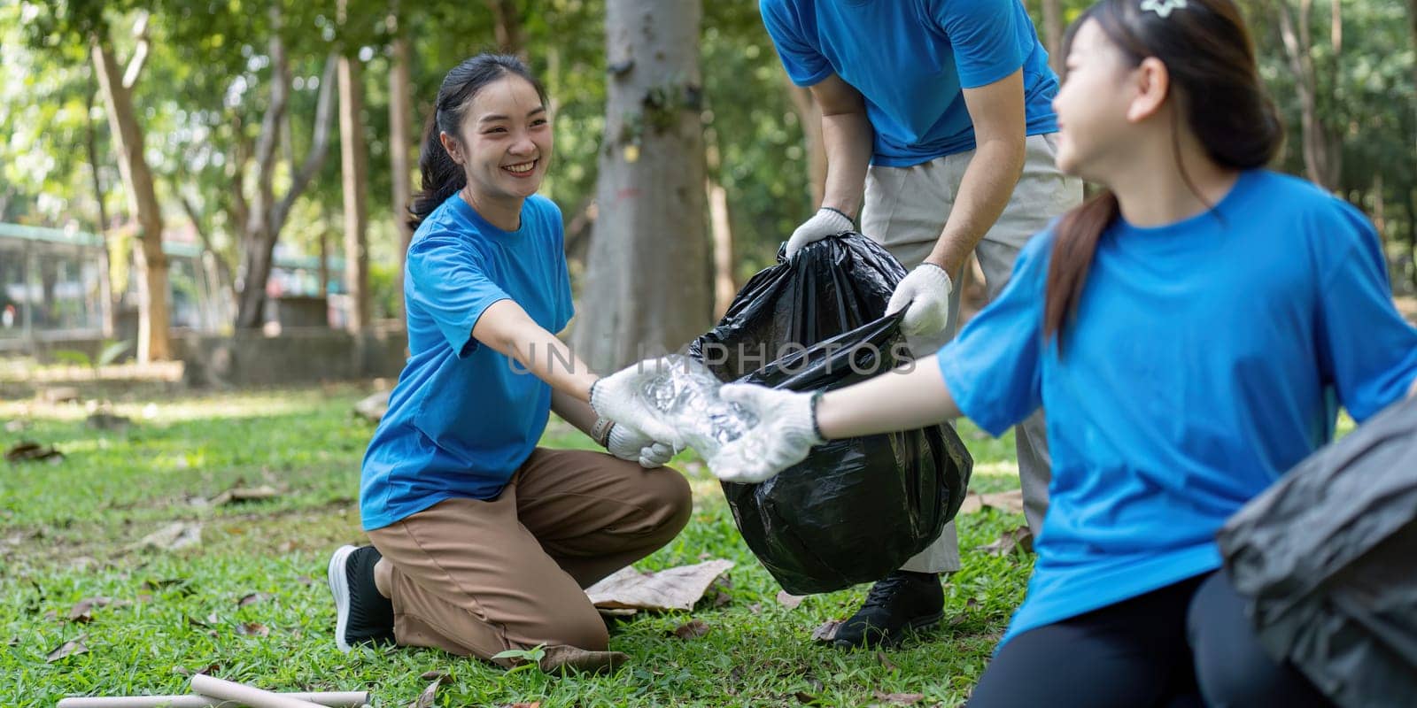 A joyful family of volunteers assists each other in gathering garbage in a park, showcasing teamwork and commitment to the environment.
