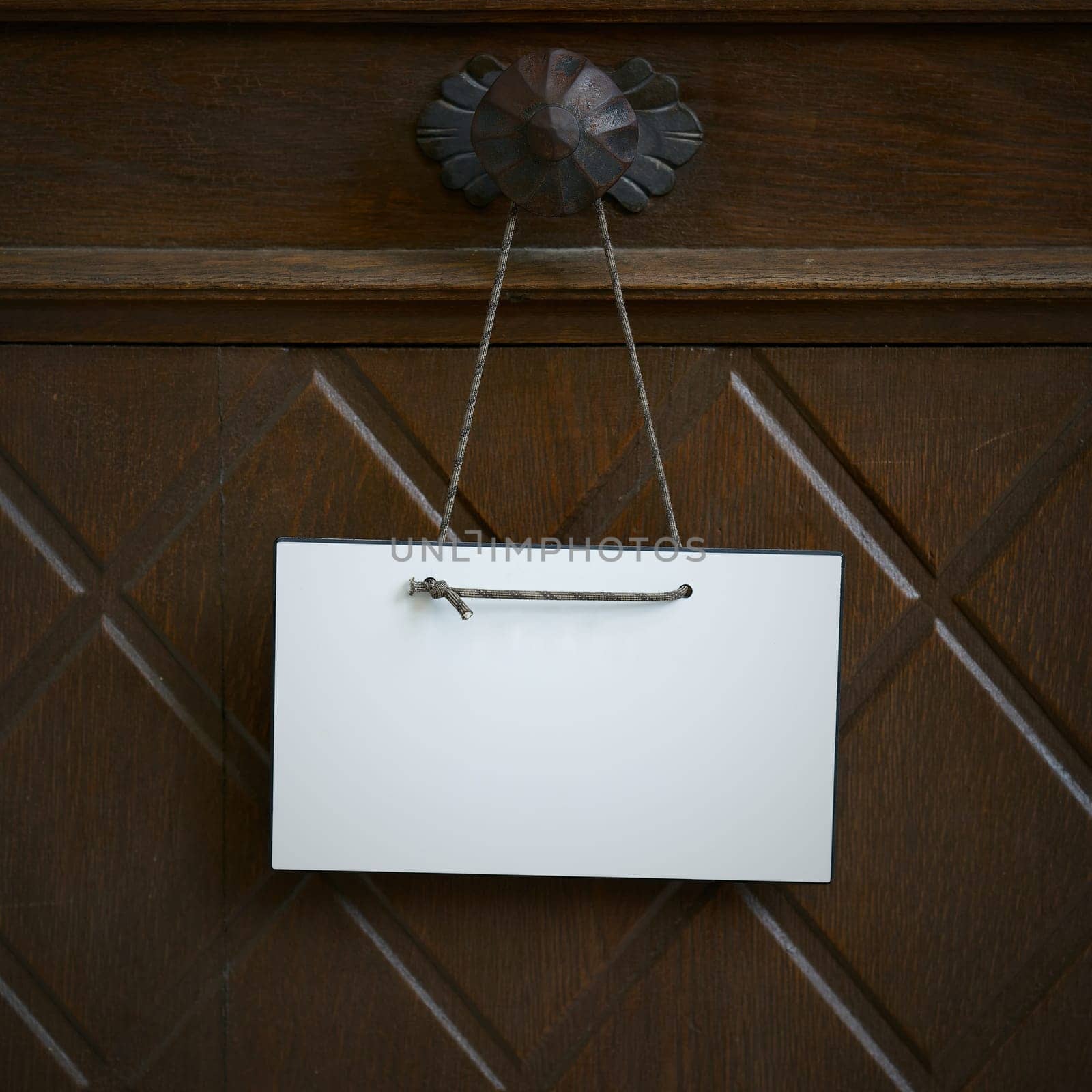 blank white sign with space for text hangs on an entrance door