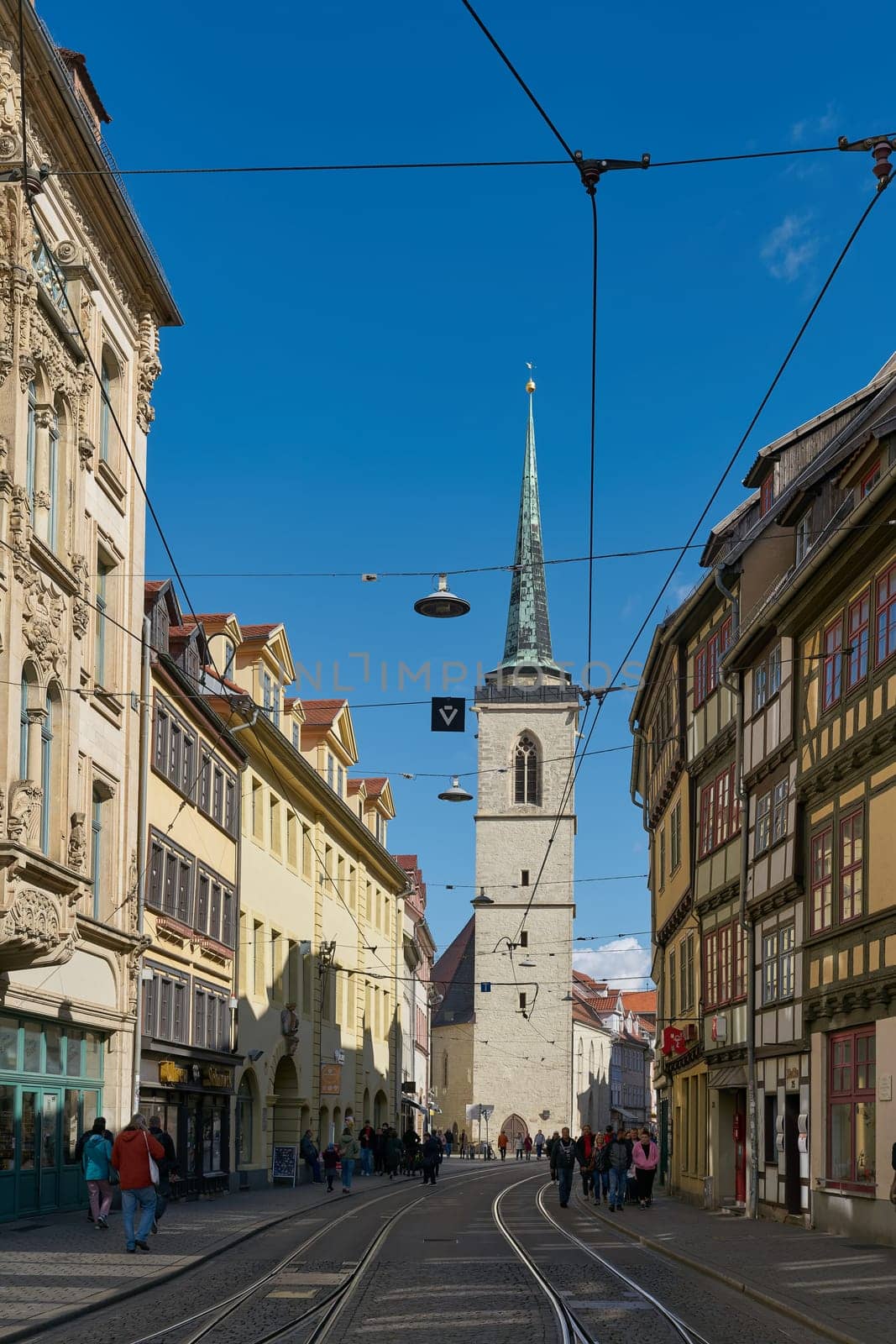 Erfurt, Germany – September 29, 2024: Shopping street with historic buildings and the All Saints' Church, Allerheiligenkirche in the old town of Erfurt in Germany