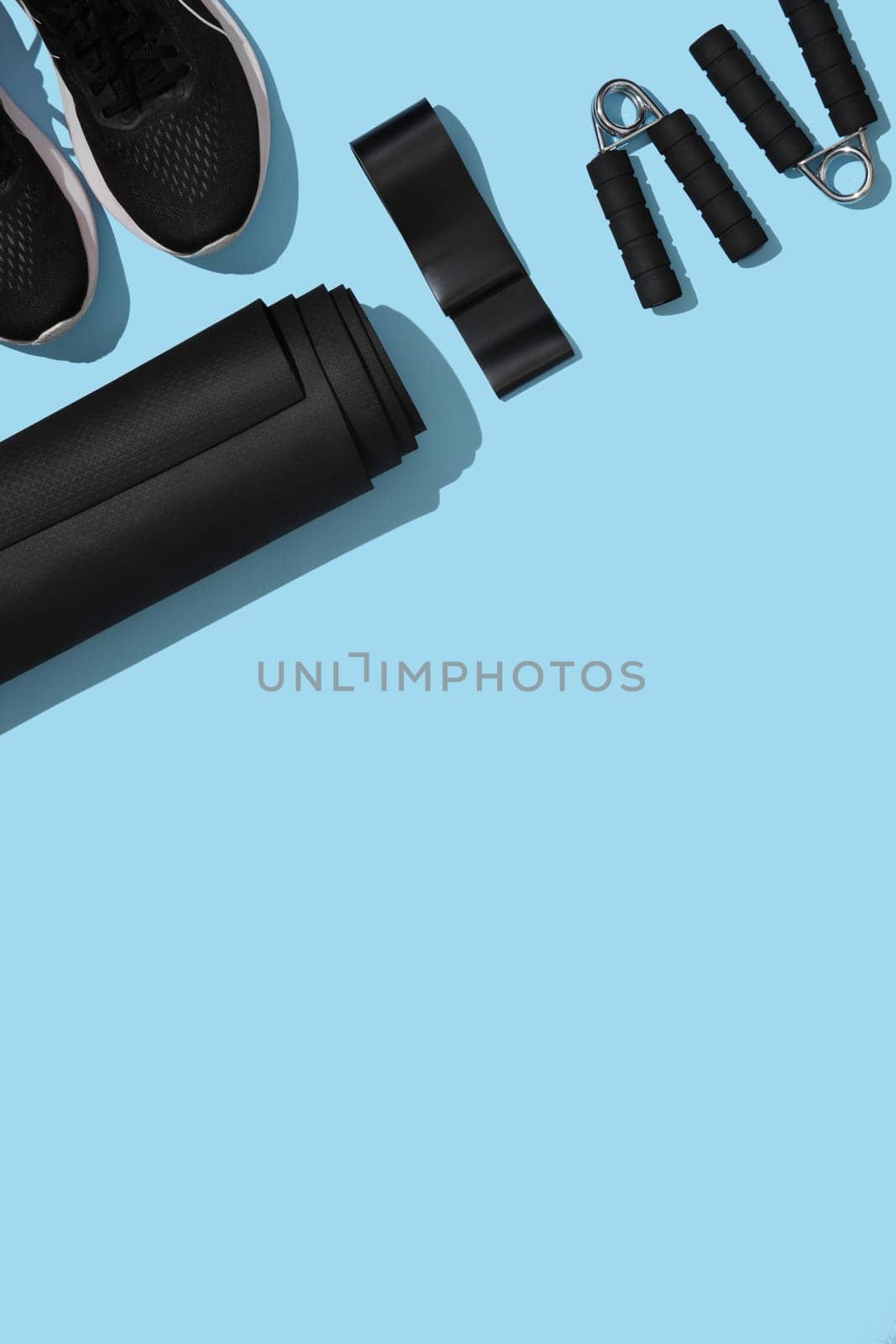 Sports background with mat, fitness elastic band, hand grips on blue background. Fitness, sports items, healthy lifestyle concept. Space for your text
