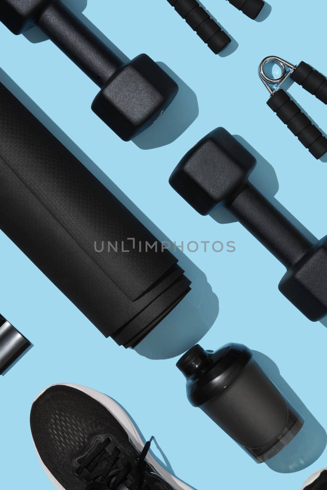 Black workout equipment for training at home on light blue background. Fitness, sport items, healthy lifestyle concept.