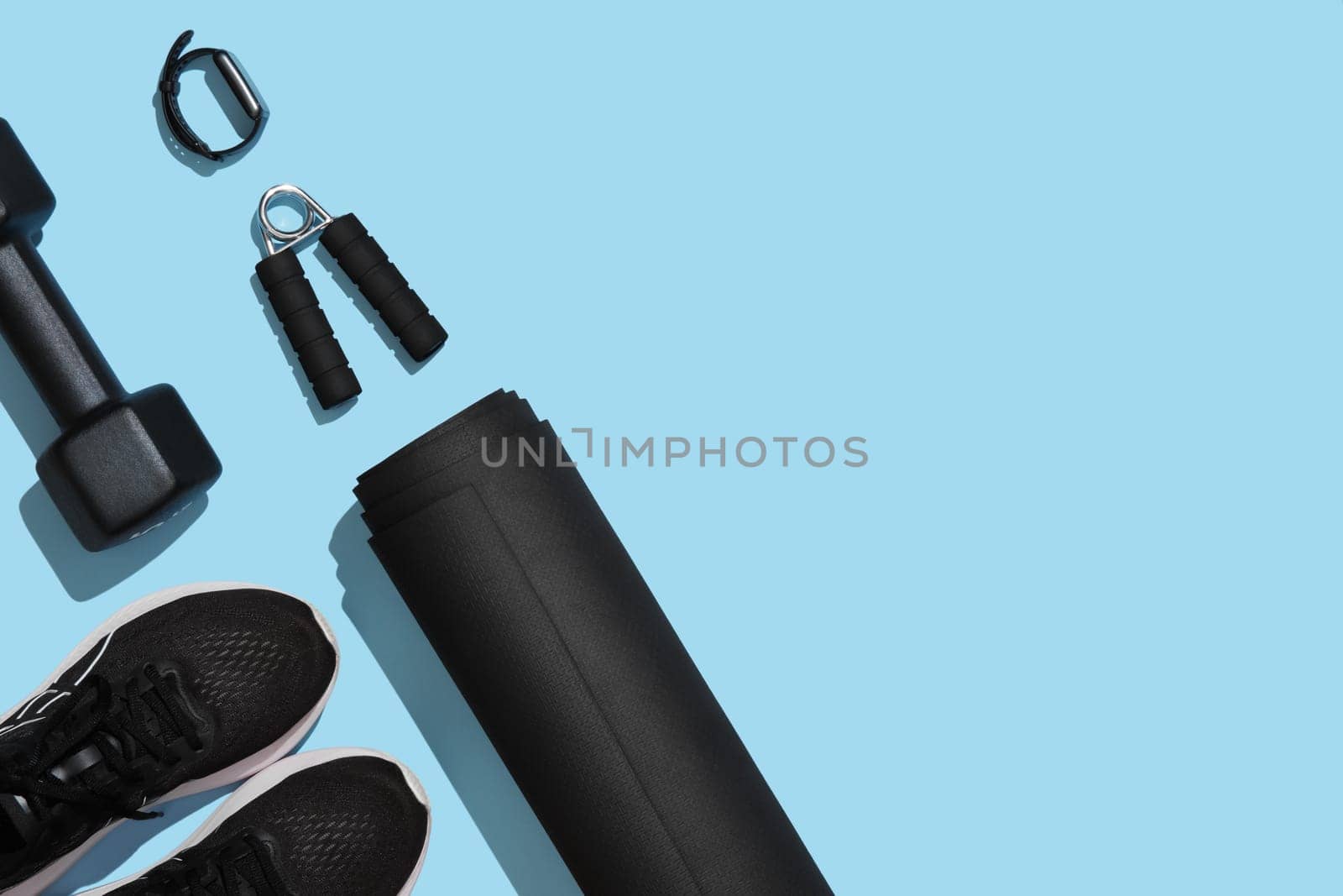 Black workout equipment for training at home on blue background. Fitness, sport items, healthy lifestyle concept. Copyspace